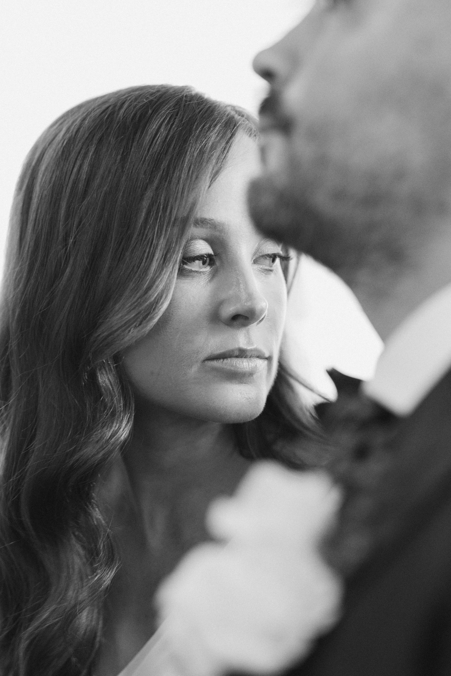 Black and white portrait of a bride gazing tenderly at a groom in a suit during a romantic wedding moment.