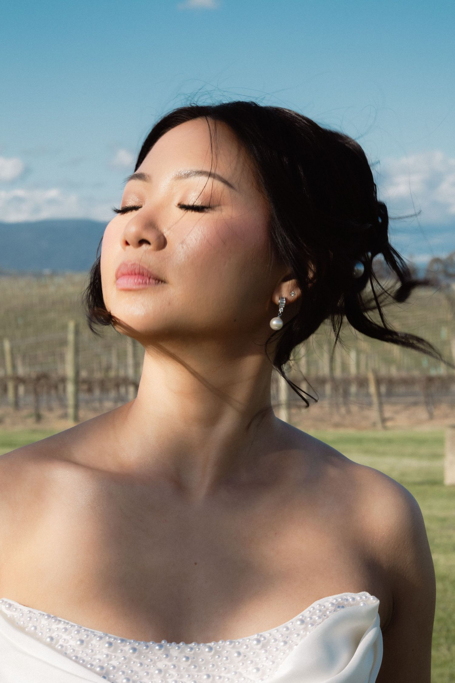 Close-up artistic bridal portraits against blue sky and mountain backdrop.