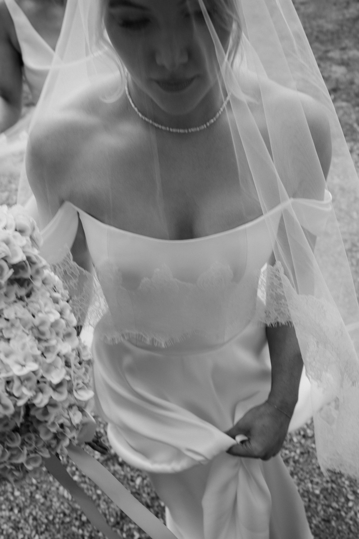 Detail shot of a flowing white wedding veil and dress against a natural outdoor background.