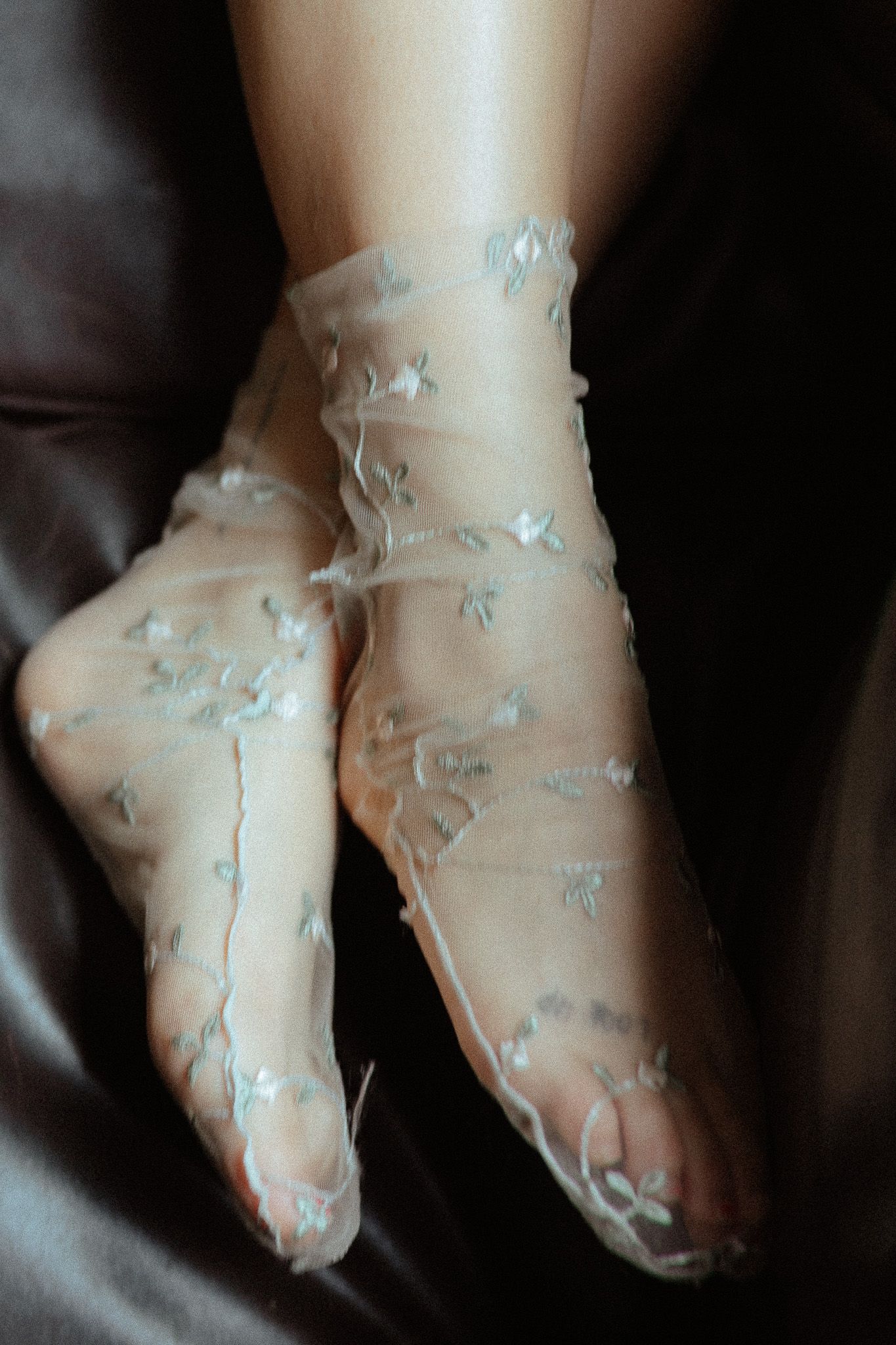 Delicate floral embroidered ballet slippers photographed against dark fabric.
