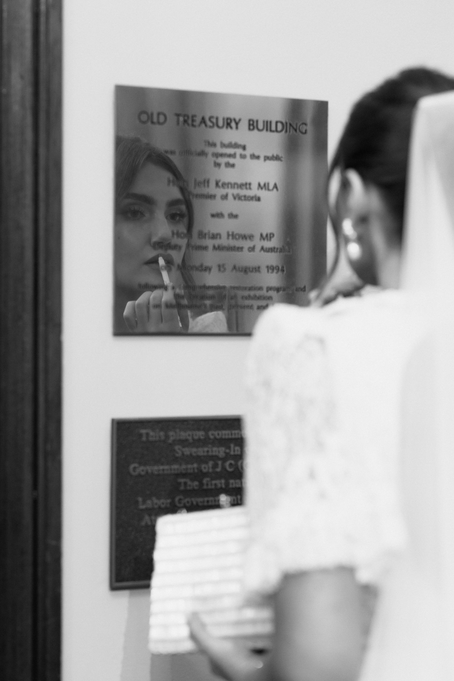 Blurred motion sequence of people walking past wall plaques in an office building.