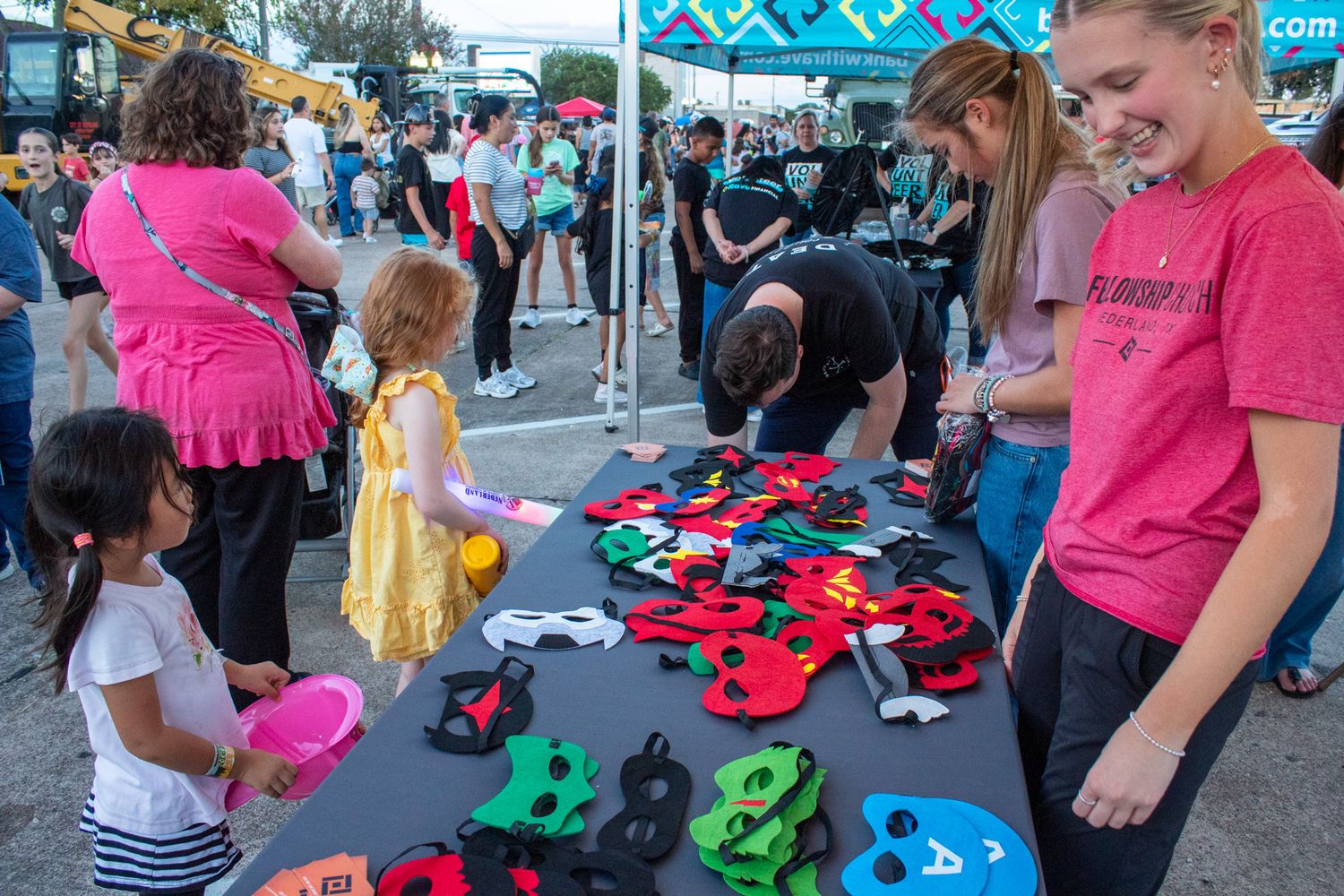 People browse through colorful clothing and merchandise at an outdoor market or street fair event.