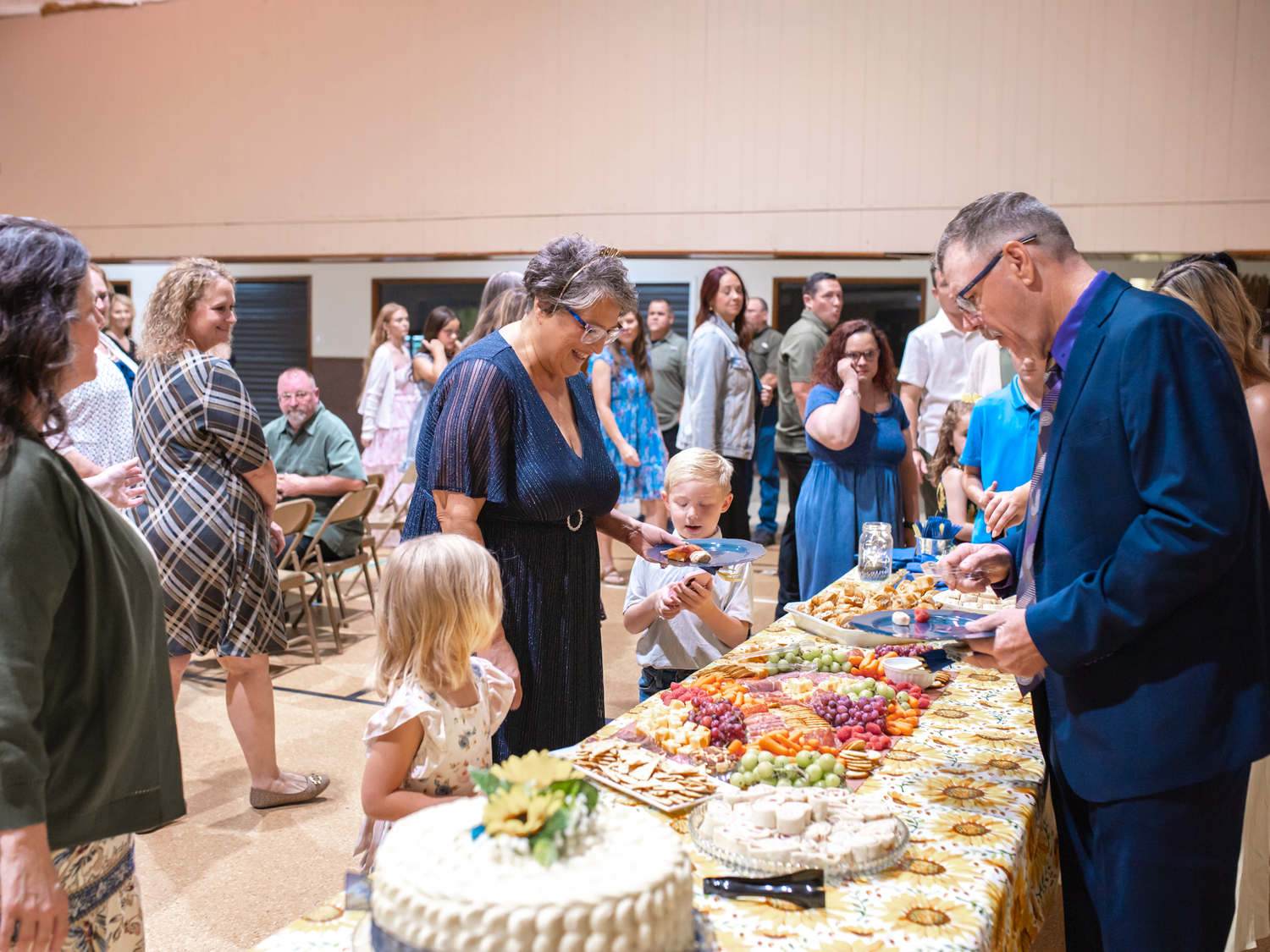 Guests gather around a lavish buffet table at an elegant indoor celebration event.