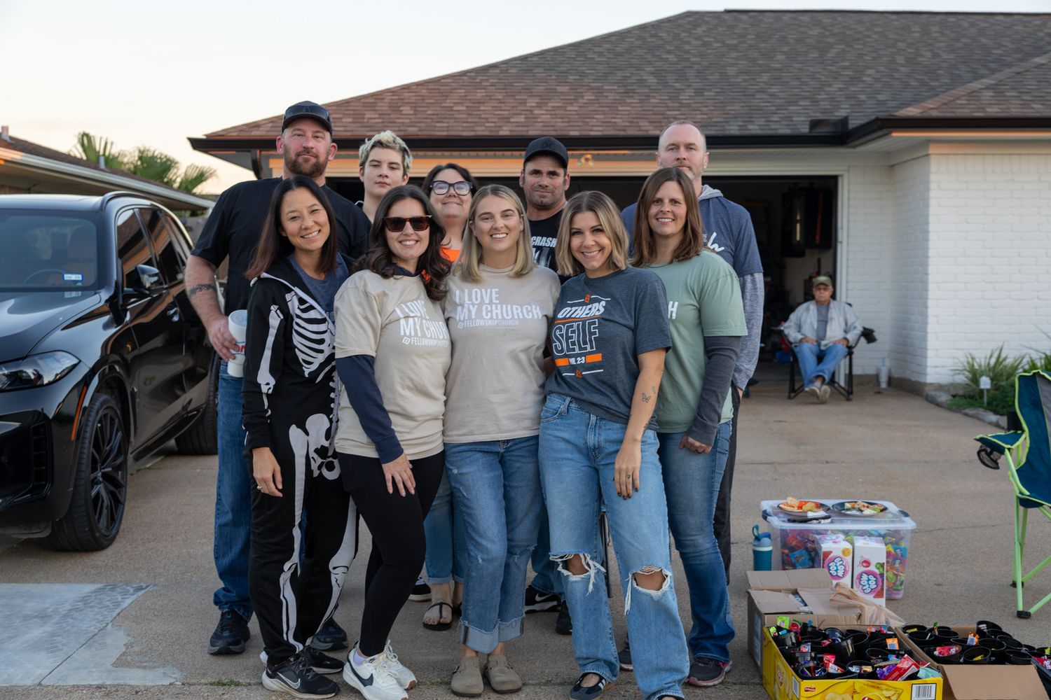 Group of friends posing together outside a home garage during a festive Halloween gathering.
