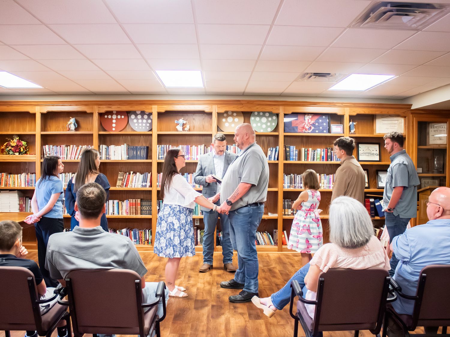 Group of people gathered in a wood-paneled library room for a formal presentation or award ceremony.