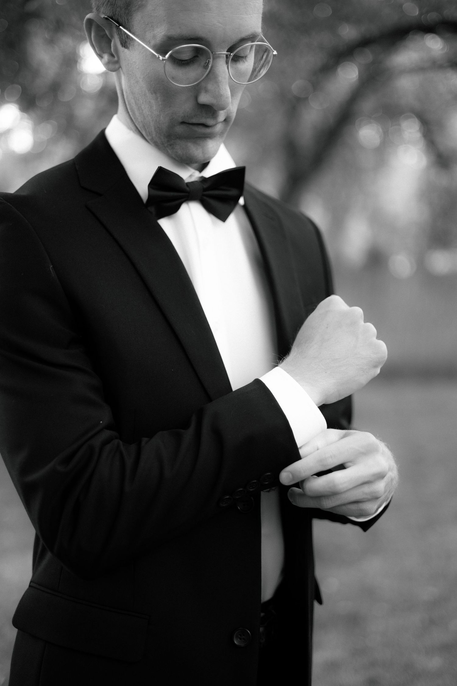 A sequence of black and white photos showing hands adjusting a formal bowtie against a dark suit.