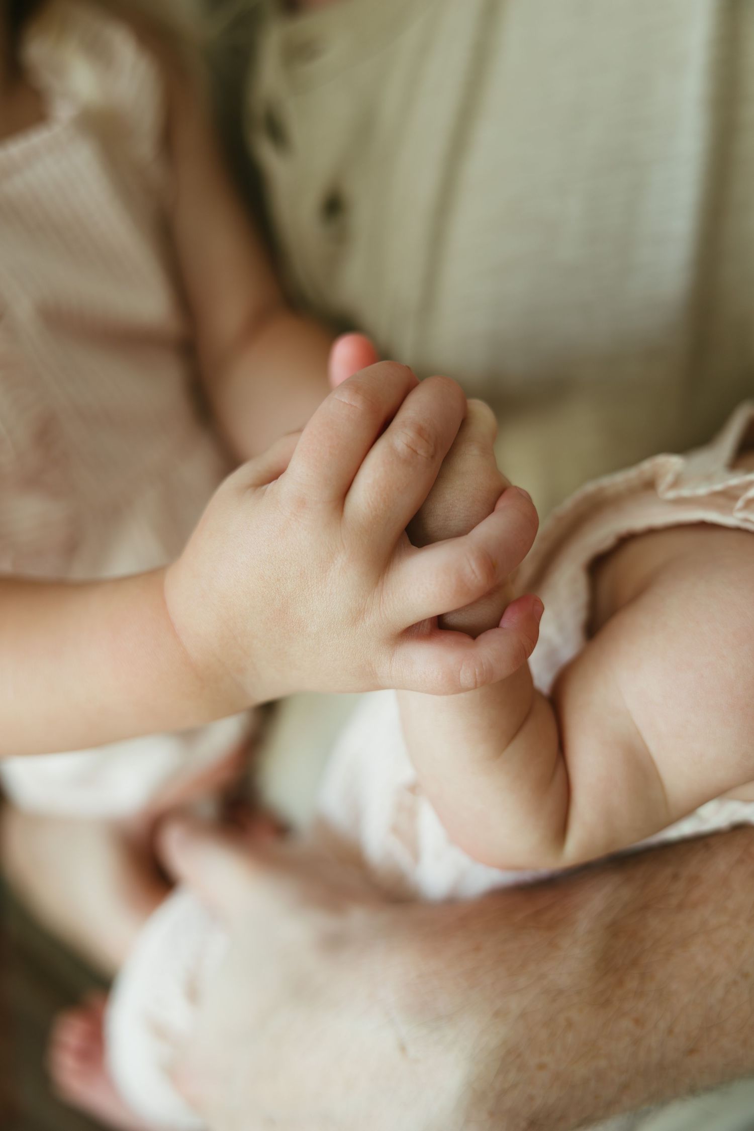 A close-up sequence of hands holding and gently grasping each other against a soft, neutral background.