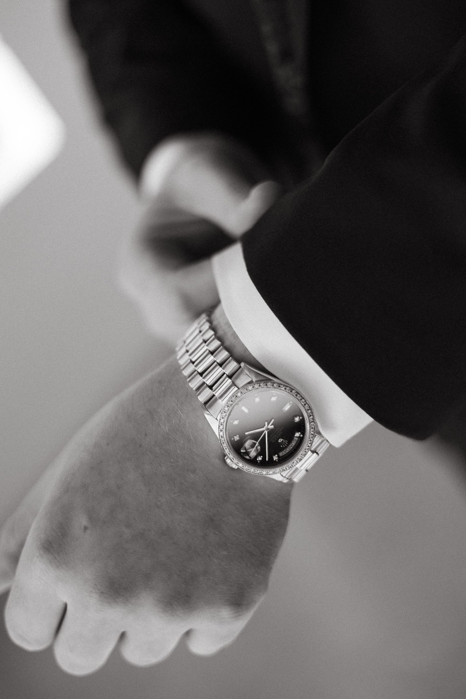 Close up black and white photo of a silver watch on someone's wrist.