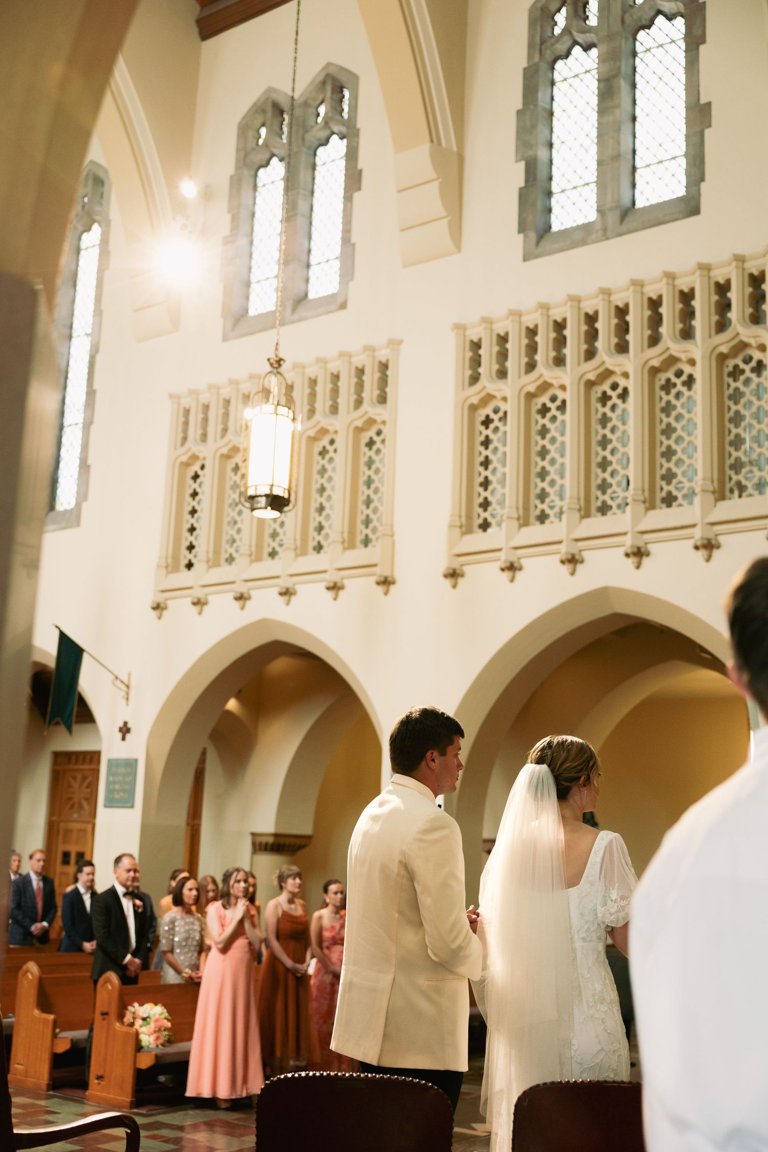 Interior of a grand church with gothic arches and stained glass windows during a ceremony.