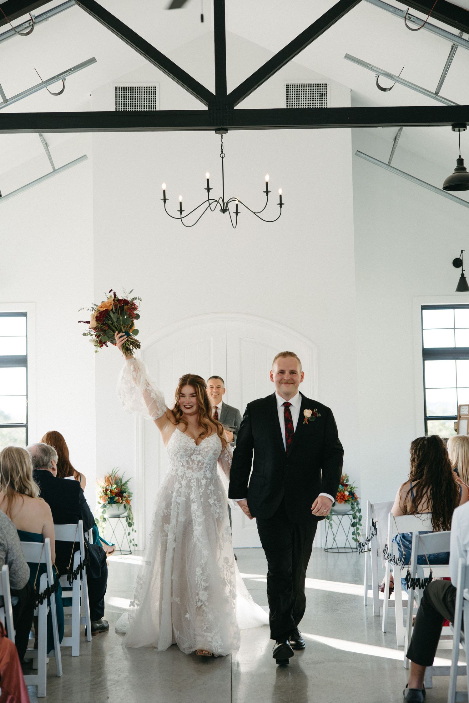 Wedding celebration in a bright modern venue with white walls and chandeliers.