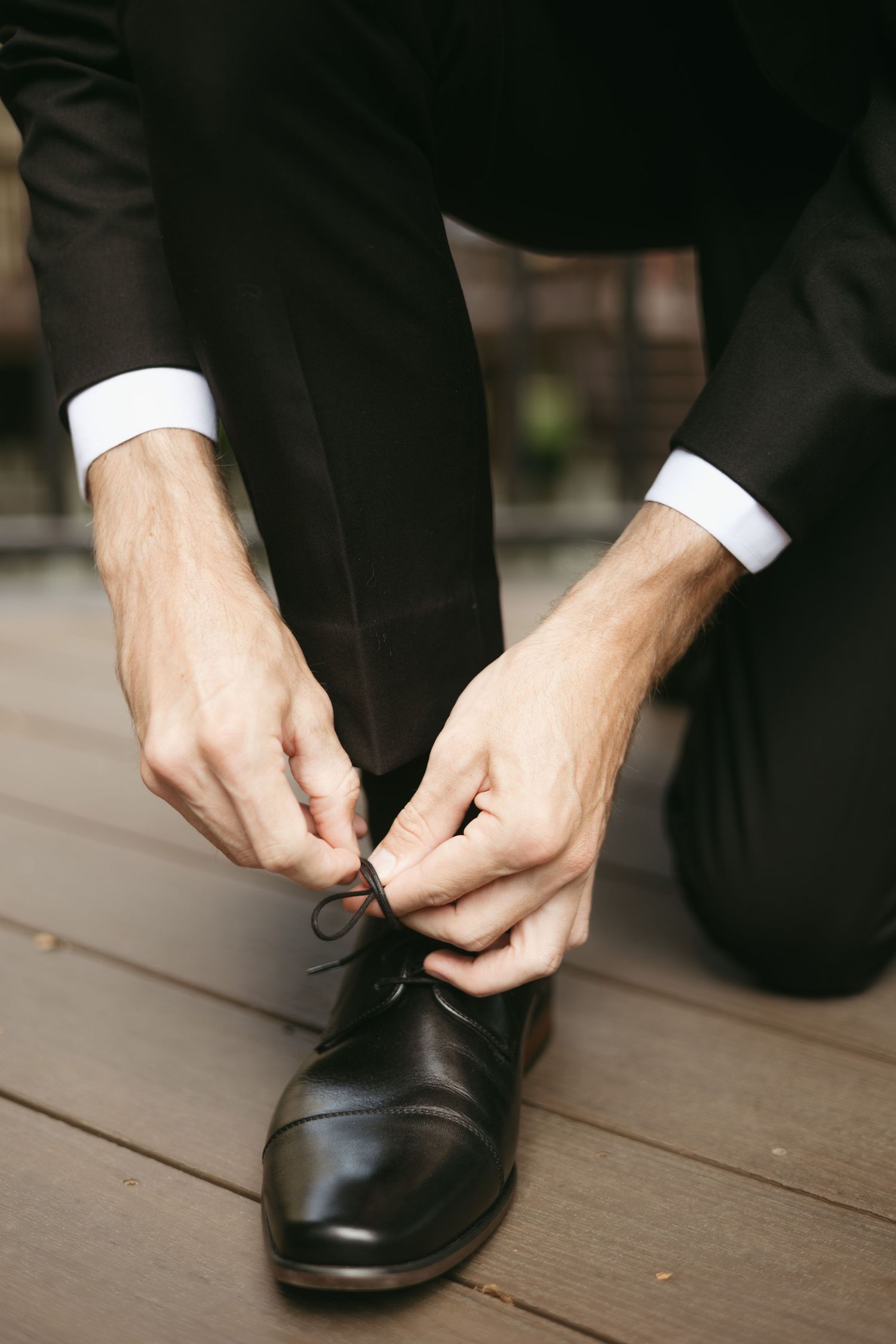 Close-up sequence showing hands tying laces on formal black leather dress shoes.