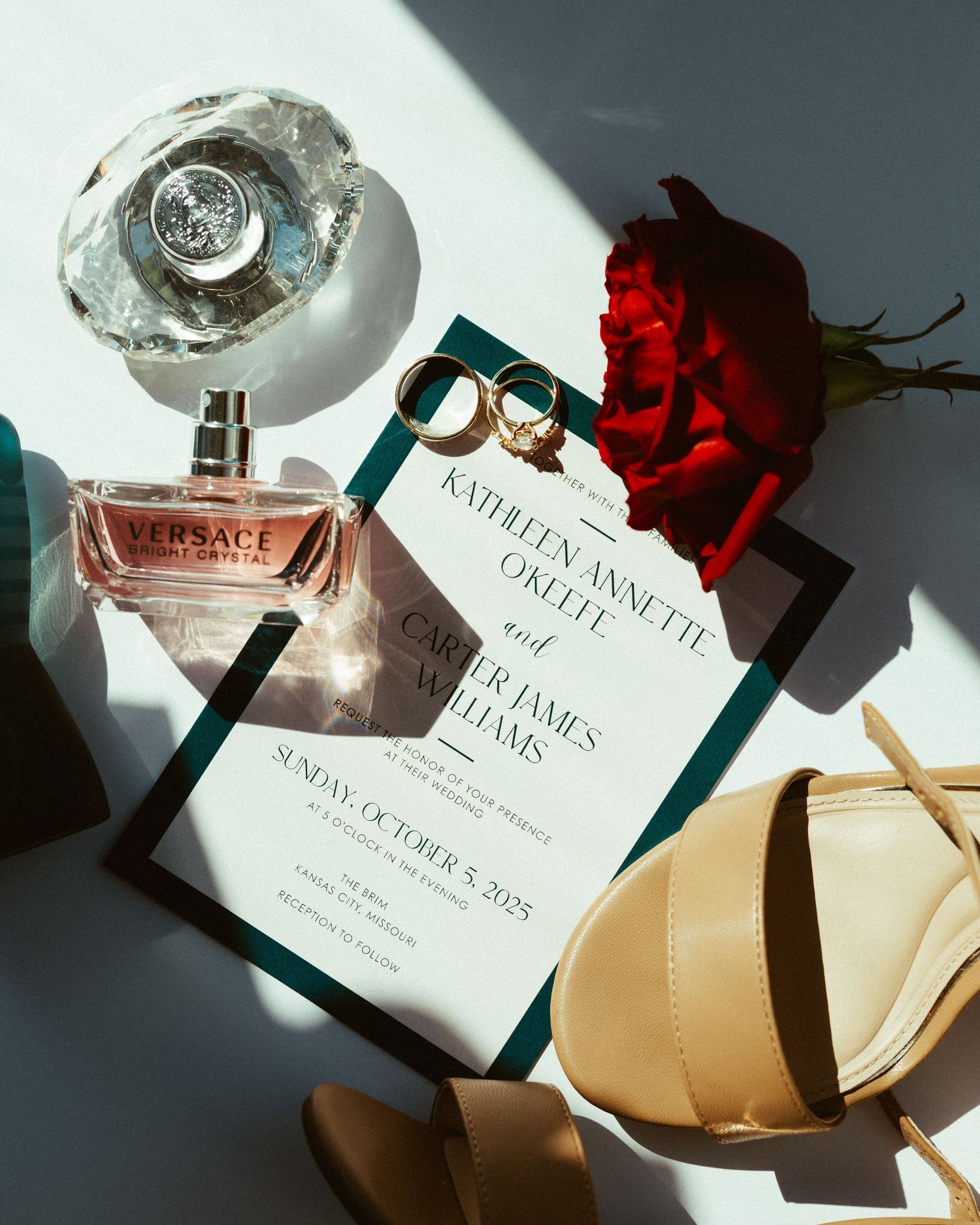 Wedding invitation with perfume bottle and red rose in dramatic lighting.