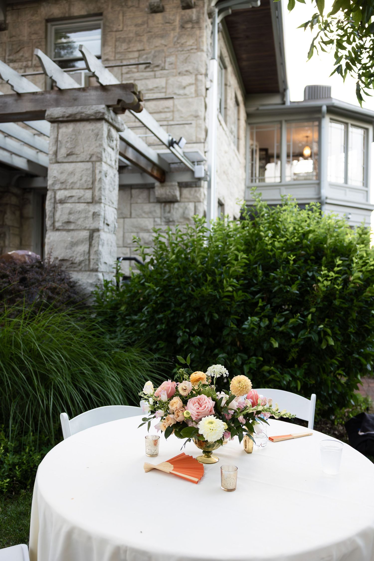 Elegant floral centerpiece on white tablecloth with stone mansion in background.