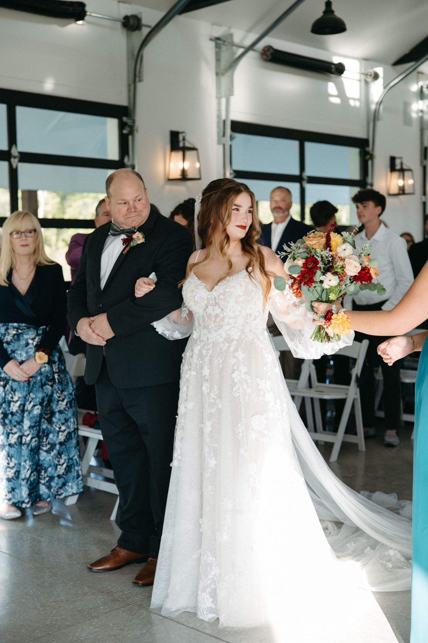 Wedding guests dancing and celebrating in a bright reception venue with white decor.