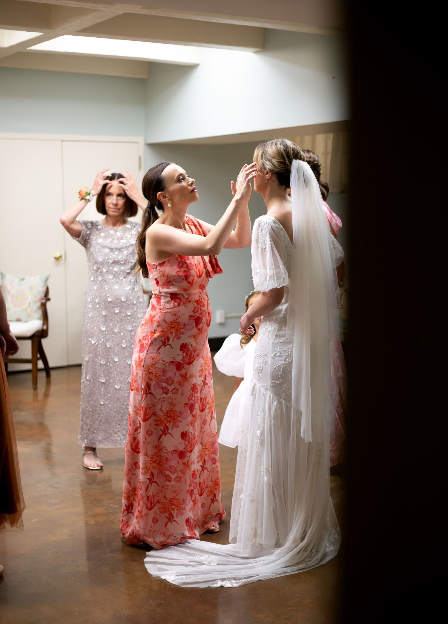 Wedding preparations showing attendants in coral dresses helping with a flowing white veil.