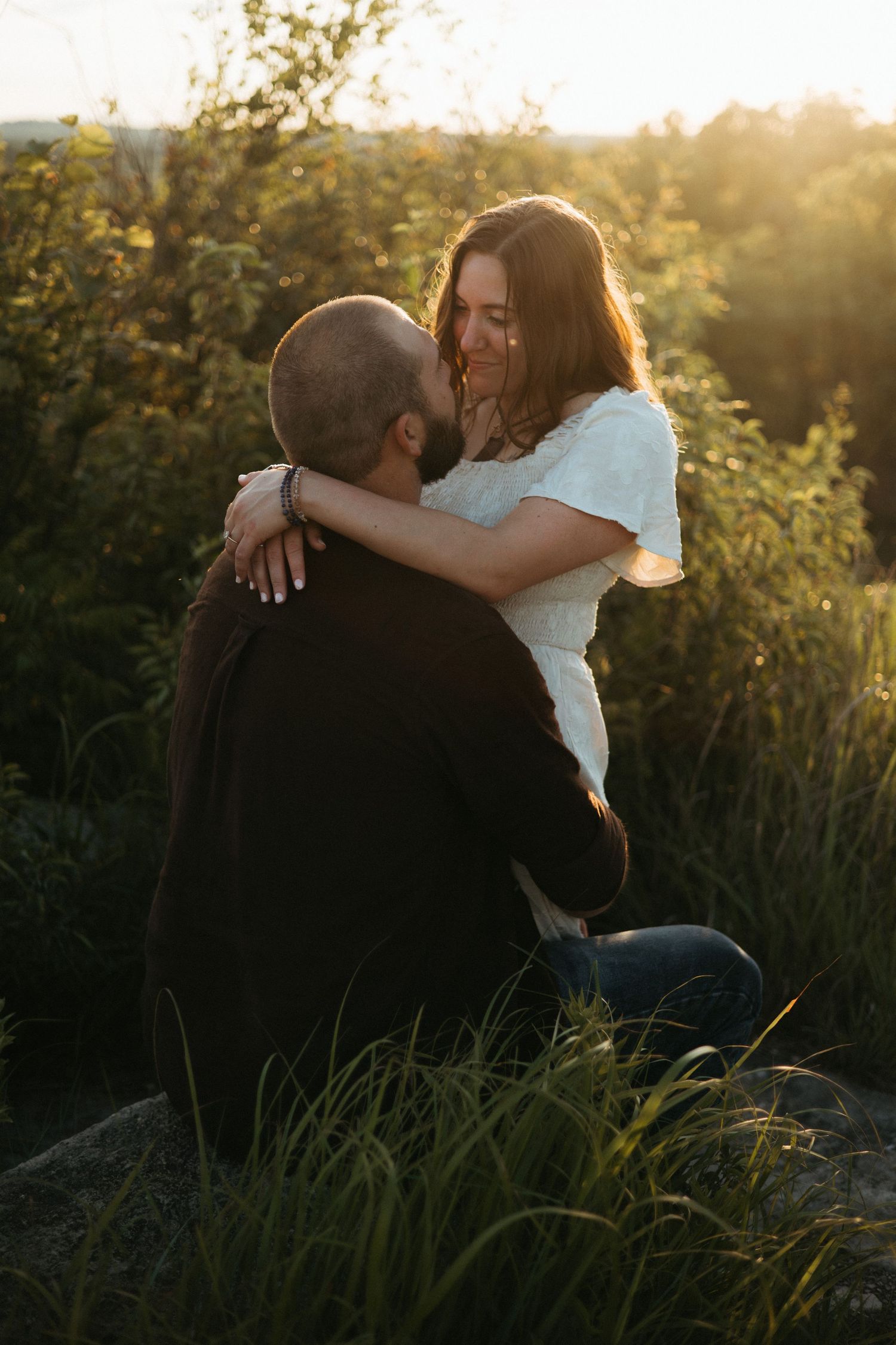 A couple sharing an intimate embrace in tall grass during golden hour.