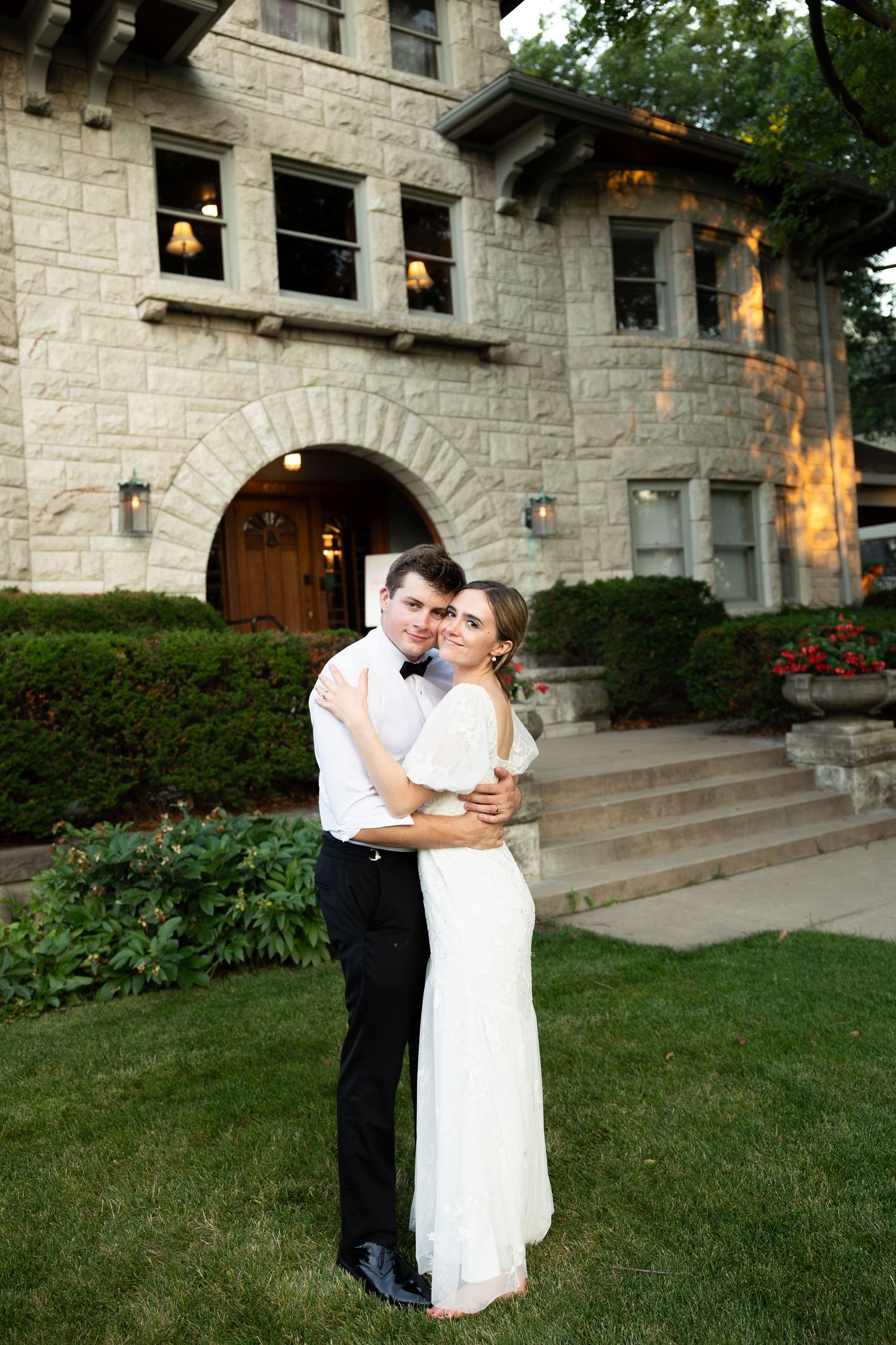 A romantic moment outside a stone mansion with arched doorway and windows.