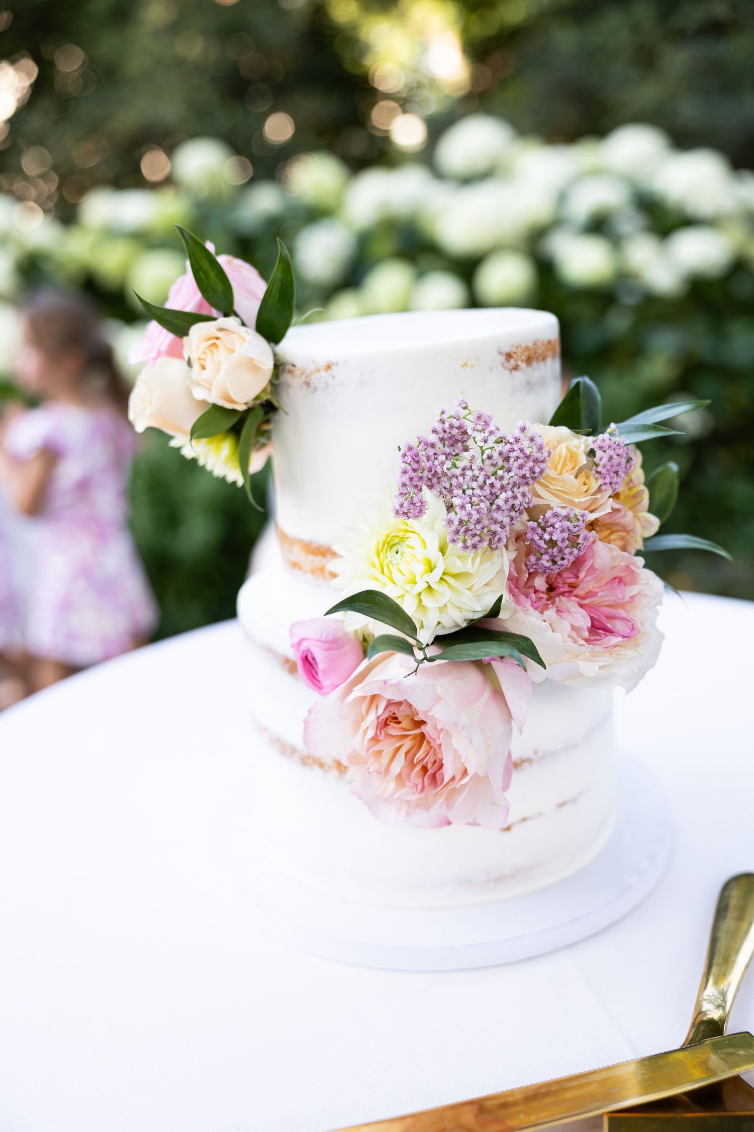 Elegant wedding cake decorated with fresh pink and peach flowers.
