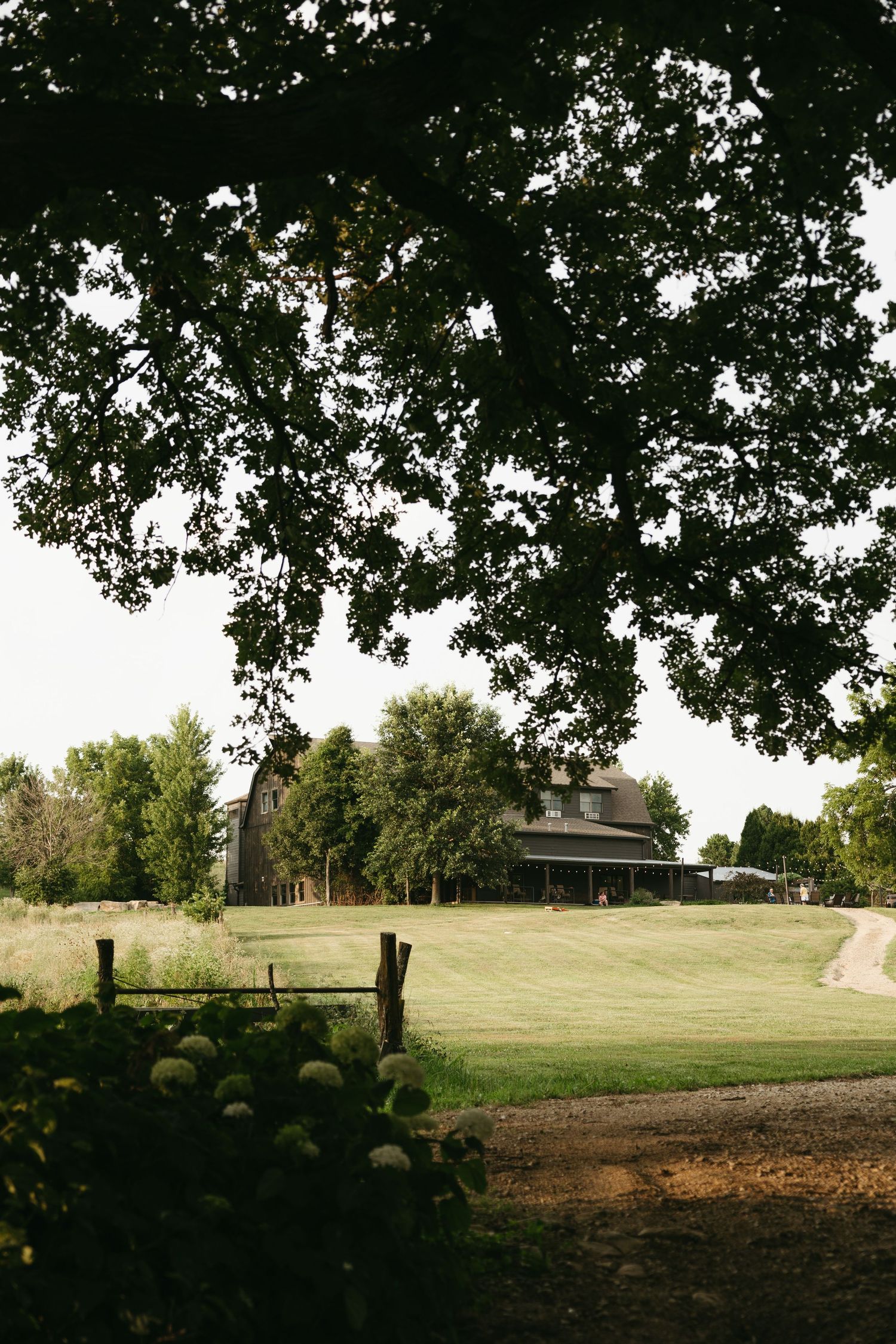 A panoramic view of a rustic countryside venue with rolling hills and mature trees.