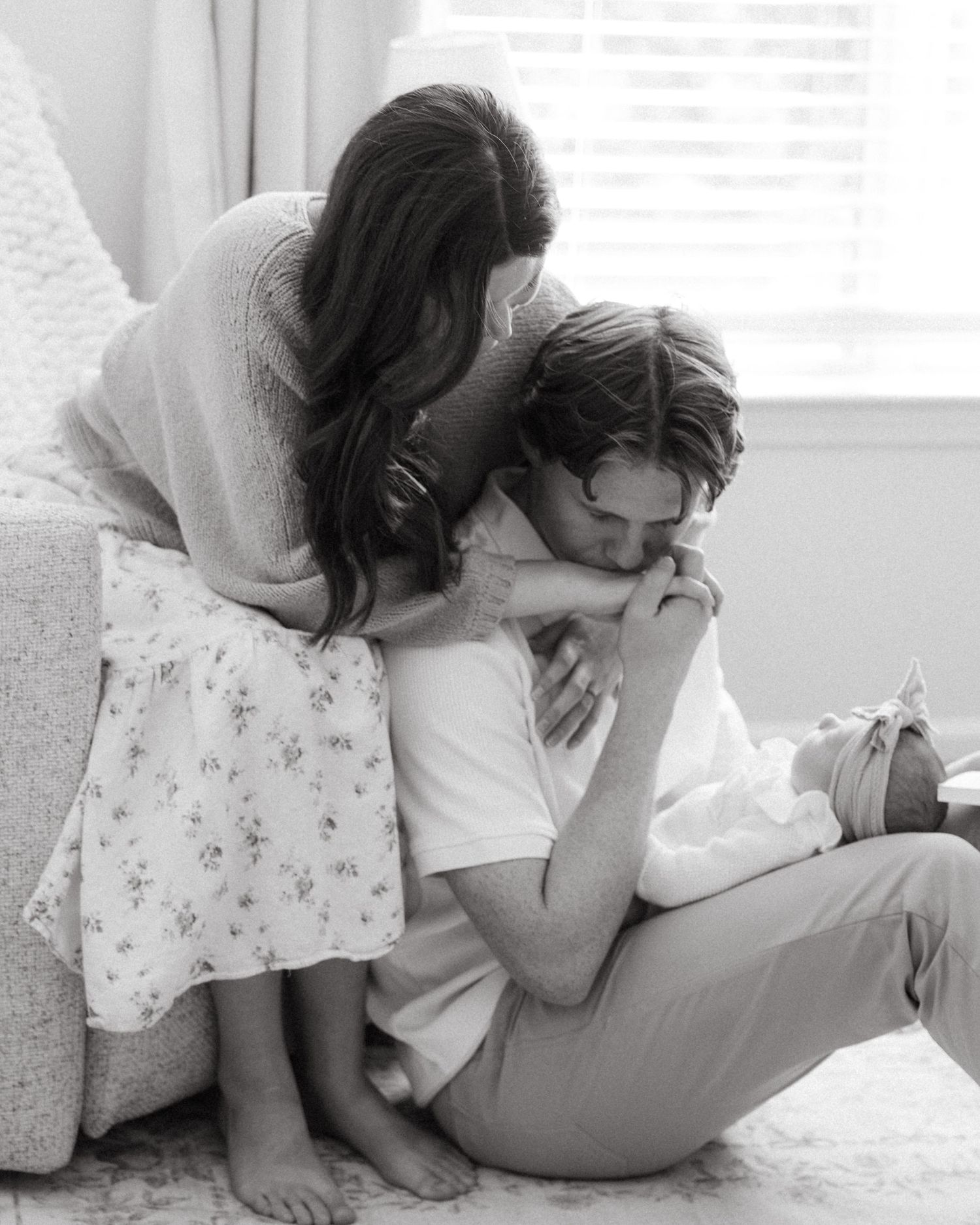 Intimate black and white family moment on light colored couch.