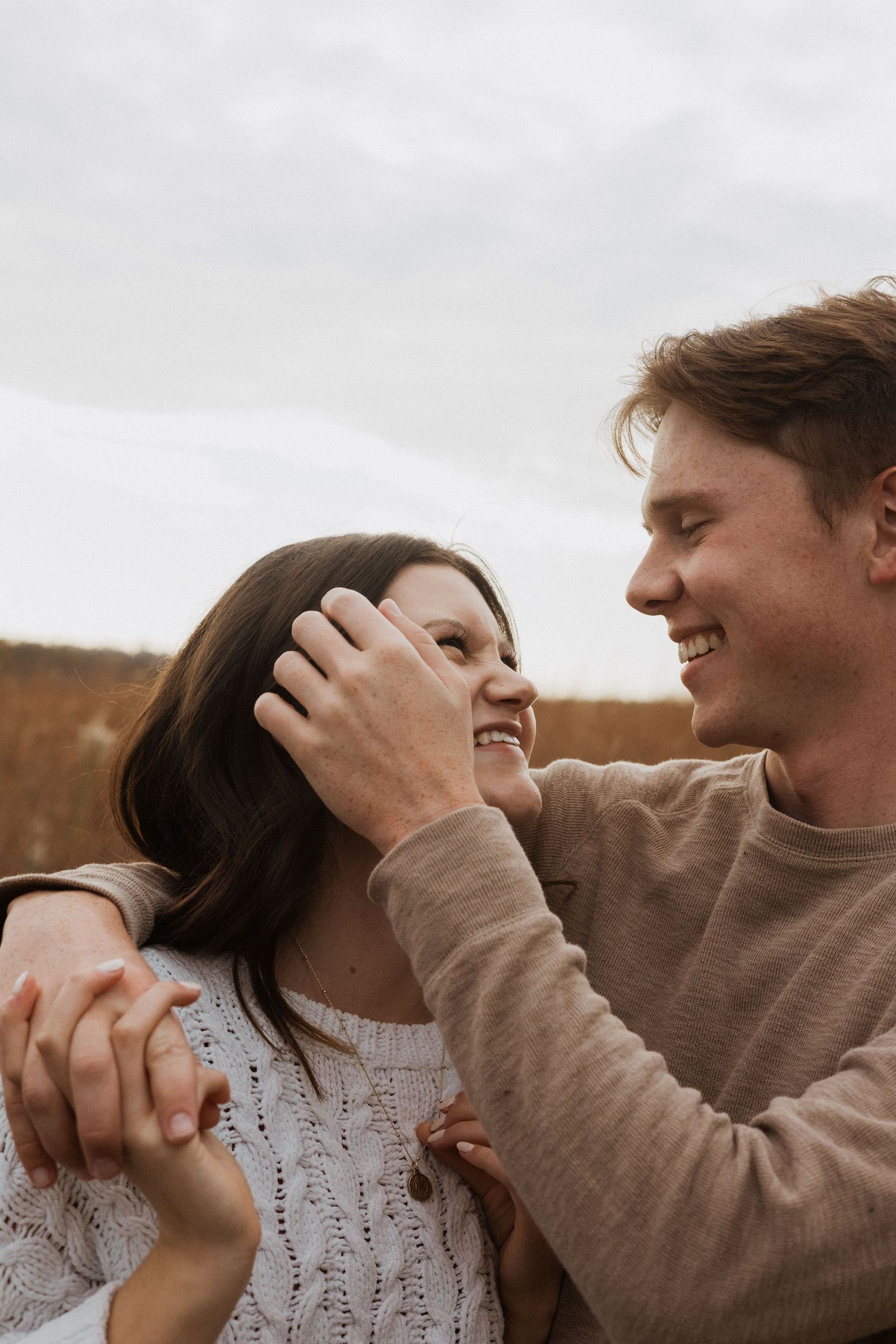 An intimate close-up series of a couple sharing tender moments against a cloudy sky.