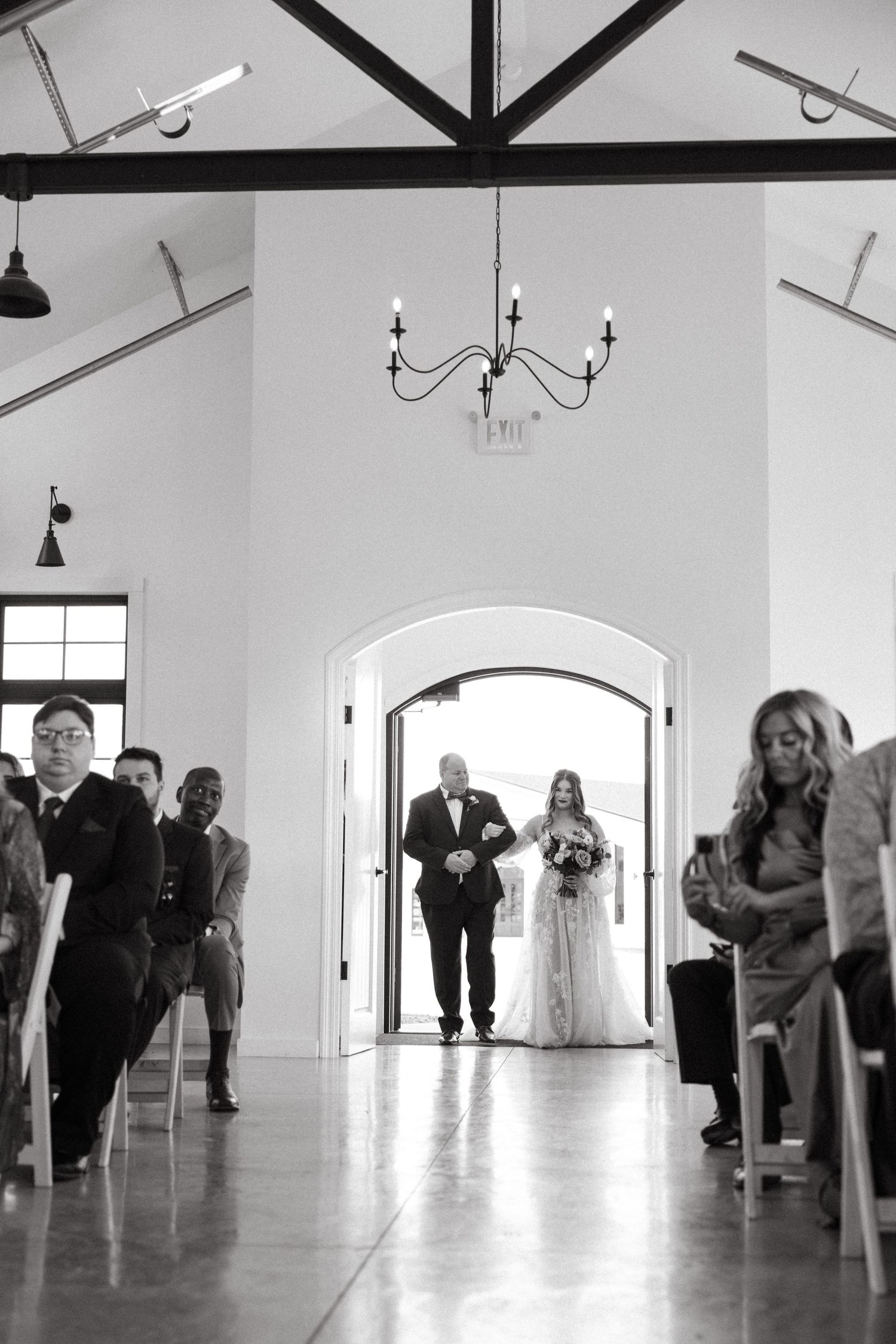 A minimalist white wedding venue interior with exposed beams and elegant lighting.