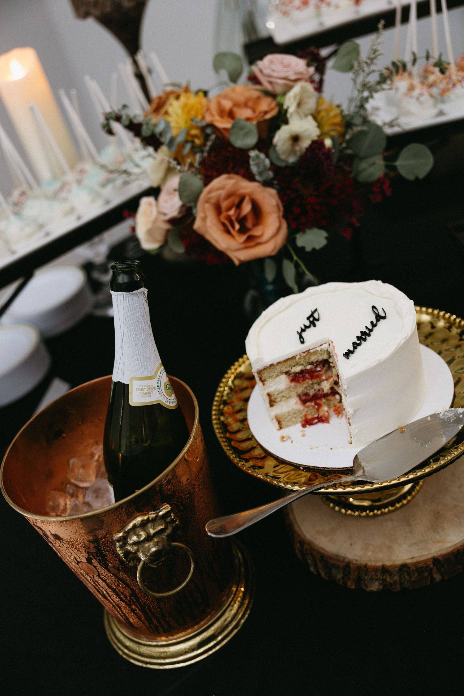 Wedding cake slices on golden plates with floral decorations and romantic lighting.