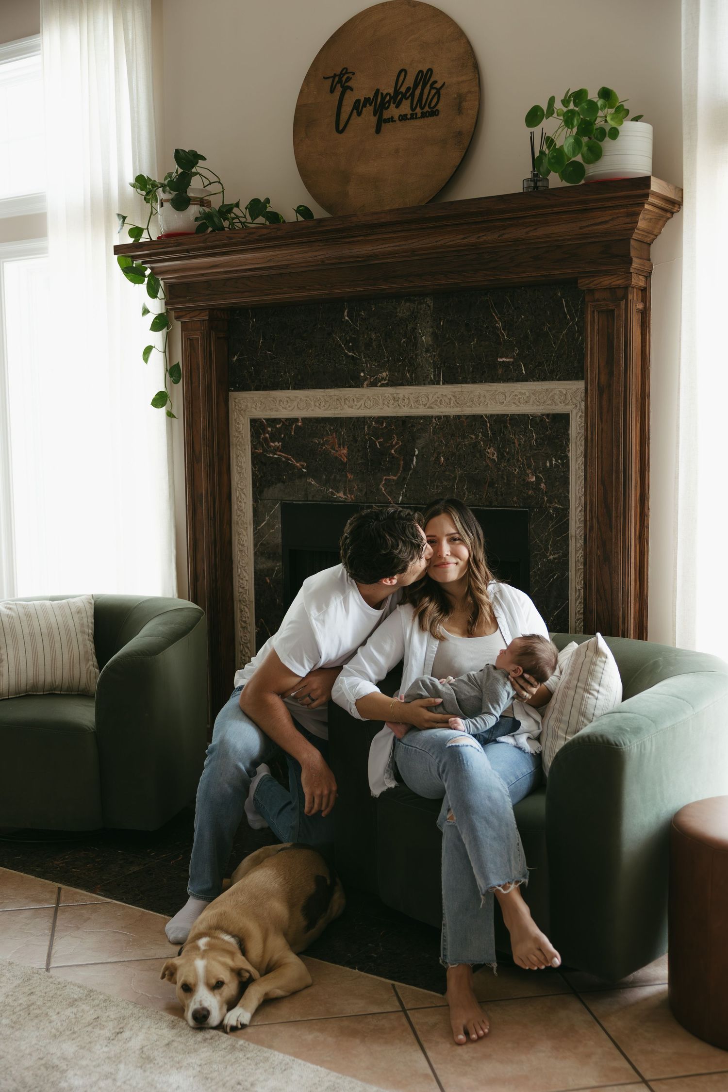 A couple relaxes on a couch at home with their golden retriever mix dog in a series of candid lifestyle photos.