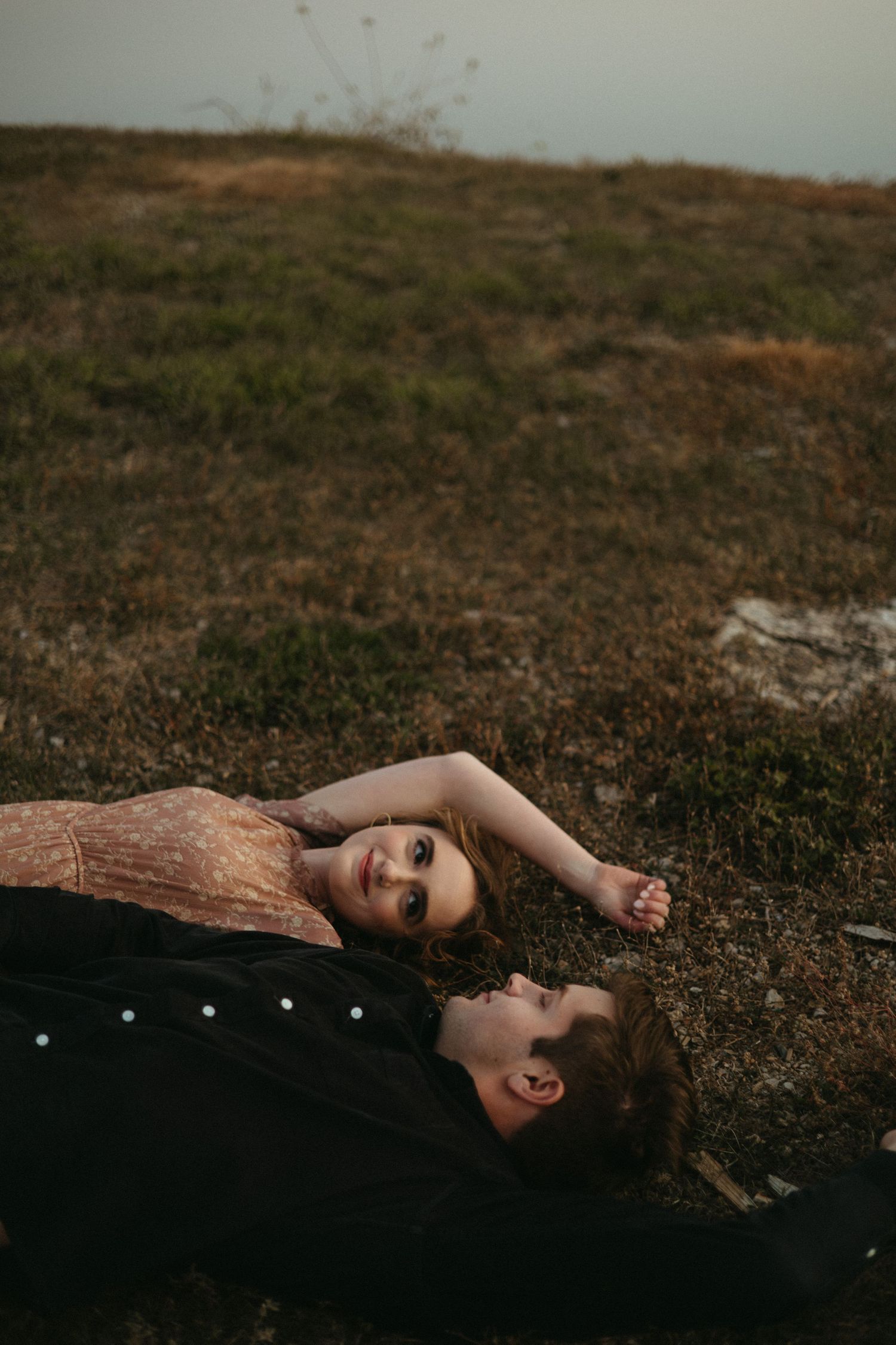 A couple lying on the ground during a romantic outdoor photoshoot.