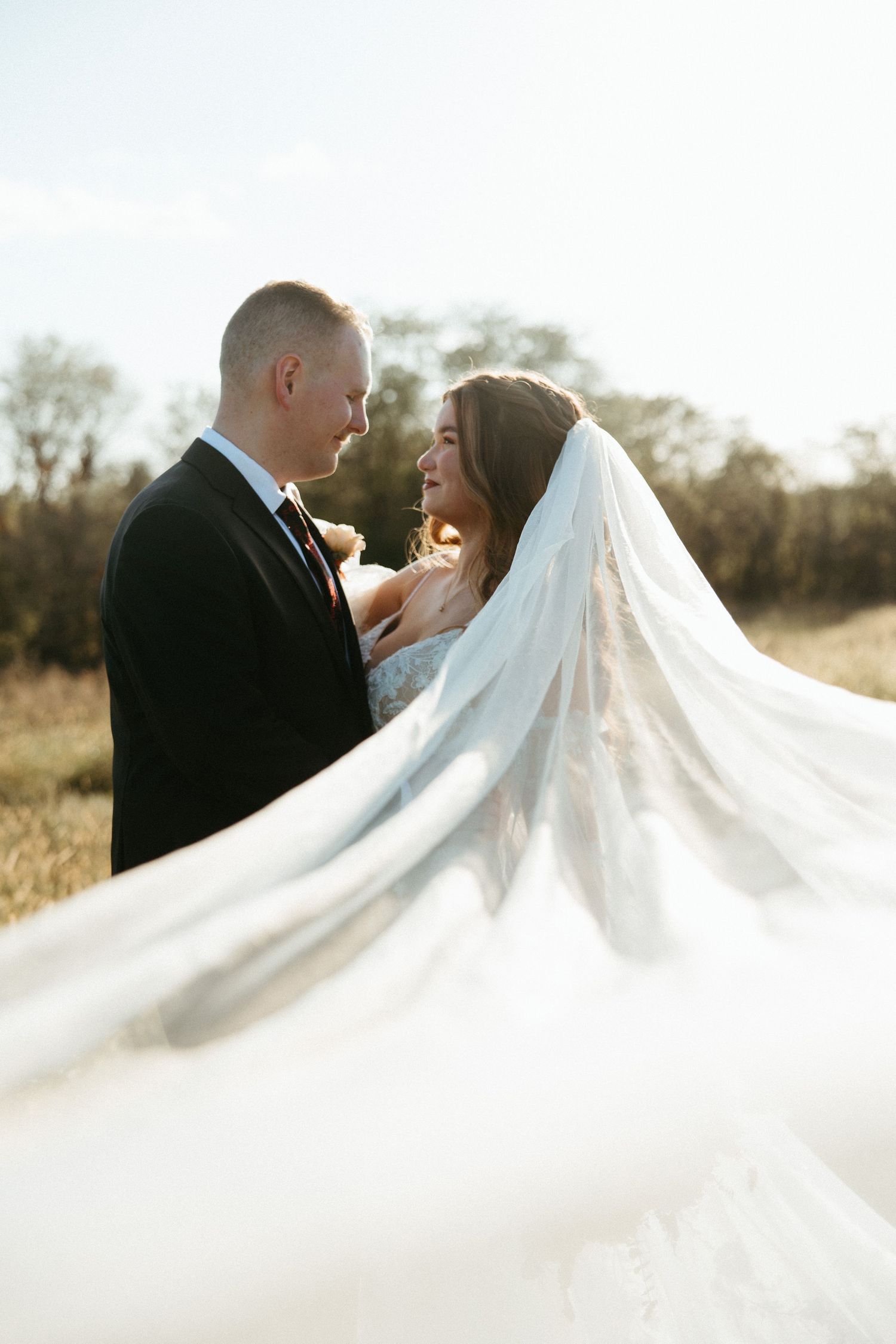 Artistic wedding portrait series featuring flowing white veil against sunlit backdrop.