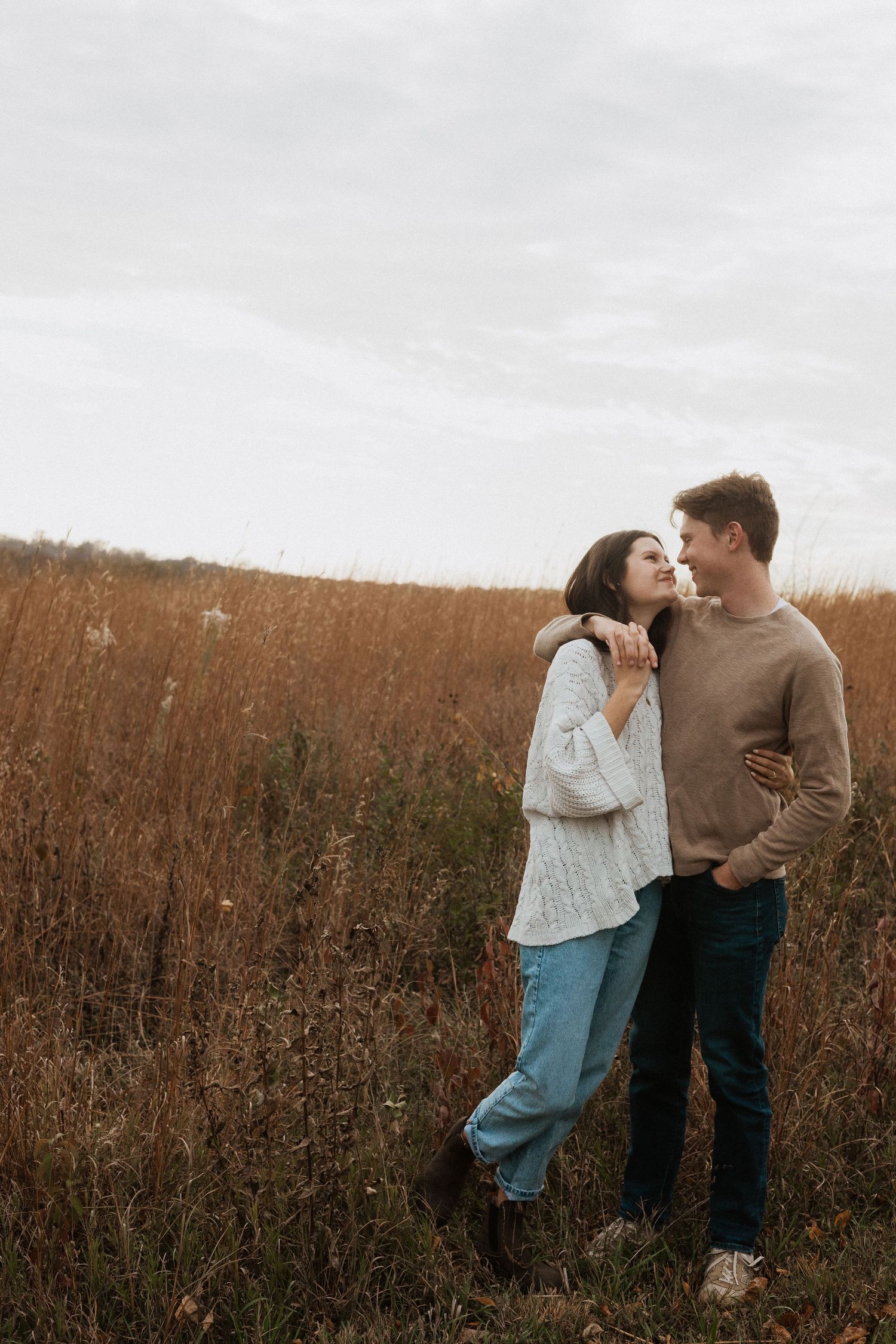 A couple shares tender moments together in a rustic autumn field during a romantic photoshoot.