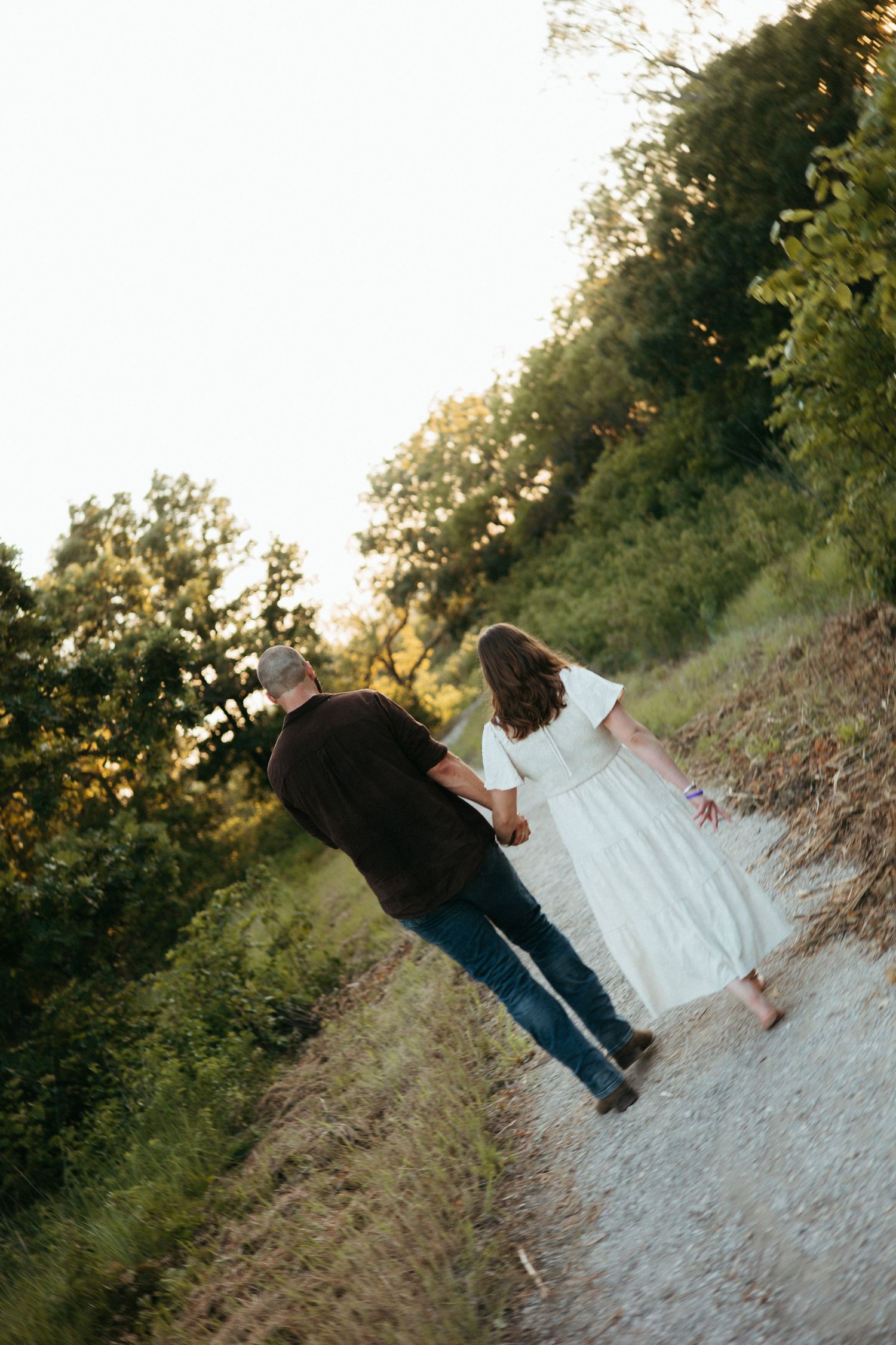Romantic couple standing together on a rocky path at sunset.