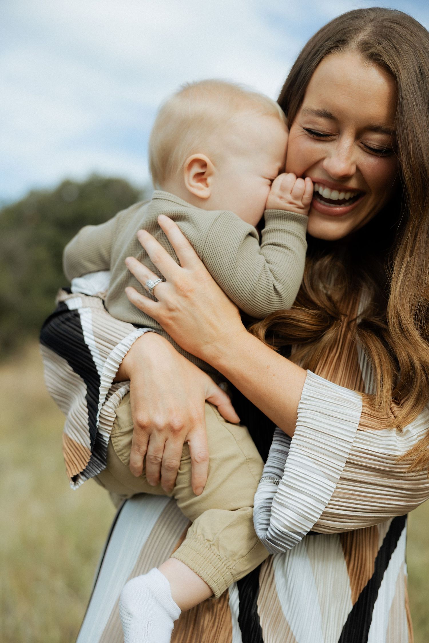 A joyful moment of affection and laughter captured outdoors in a natural setting.