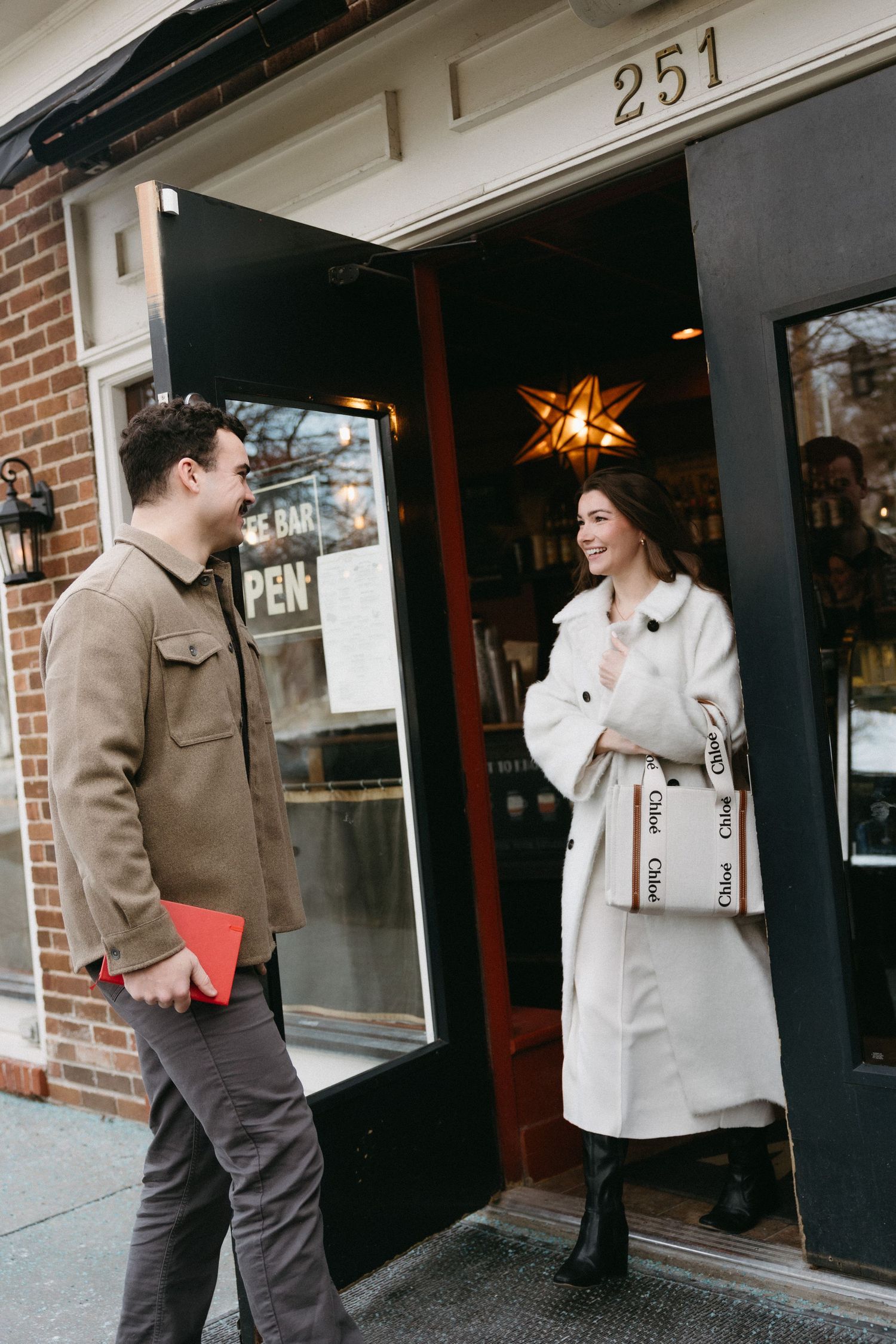 Couple walking and laughing together outside a brick storefront with vintage lighting.