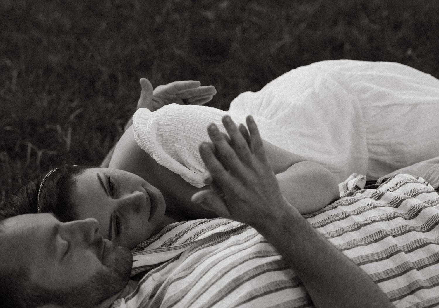 Intimate black and white portrait of a couple lying together in a tender moment.