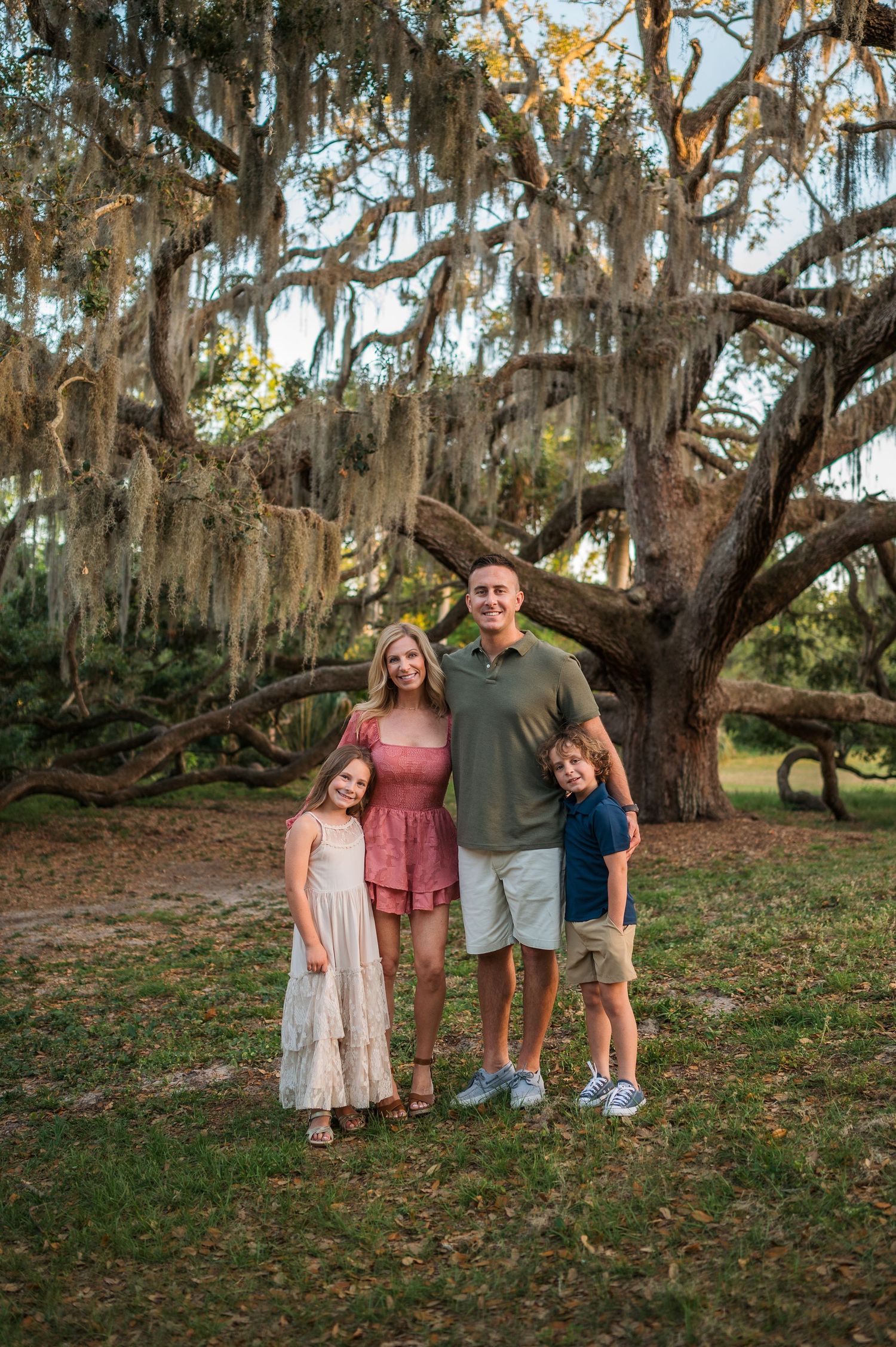 Family portrait session under sprawling oak trees with Spanish moss at golden hour.