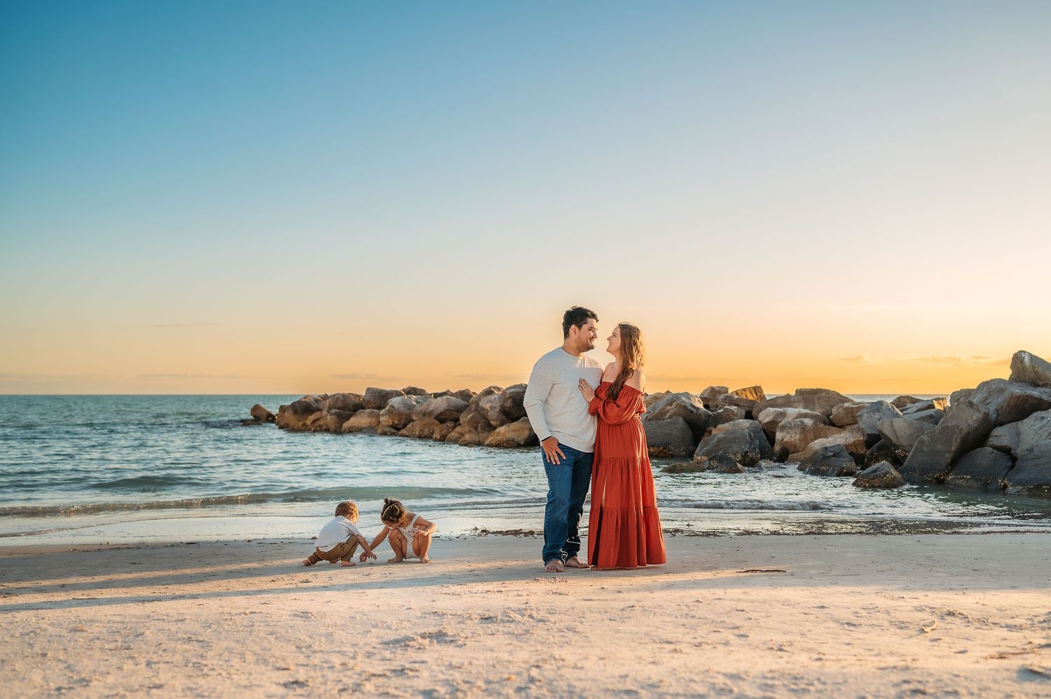 Sunset beach photography with rocky coastline and warm golden light.