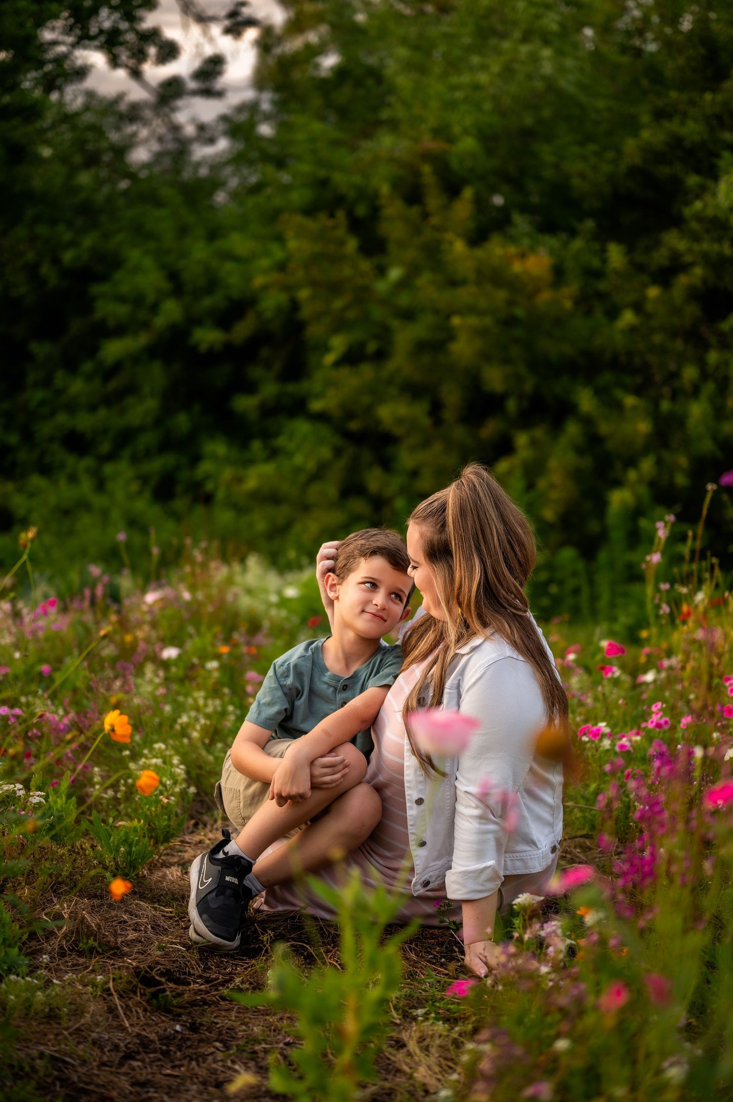 Mother and son sharing intimate moment in field of colorful wildflowers.