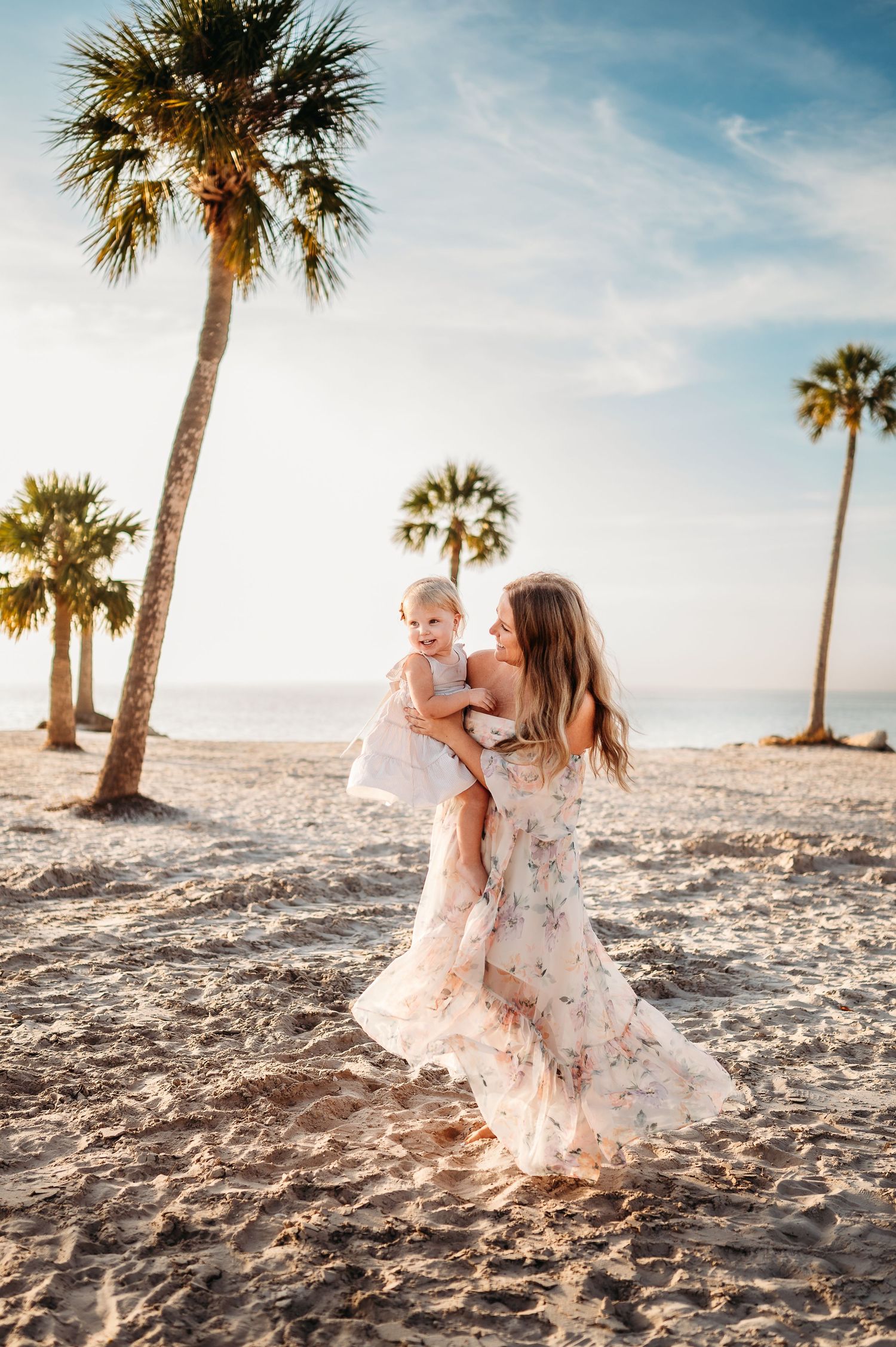 Palm trees frame a tender moment on a sunny beach with soft sand.