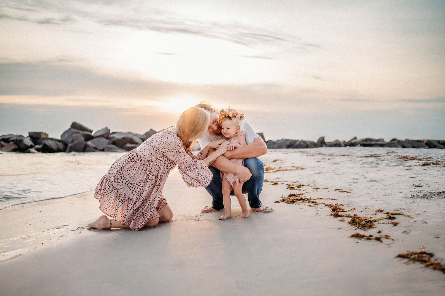 Intimate beach photography session with soft lighting and ocean waves in the background.