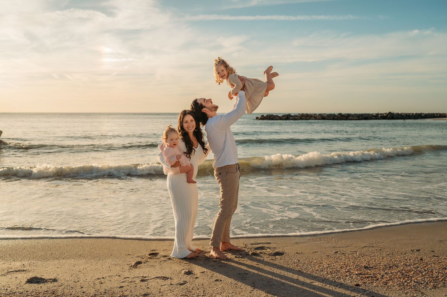 Intimate beachside moment captured during sunset with ocean waves and sandy coastline in the background.