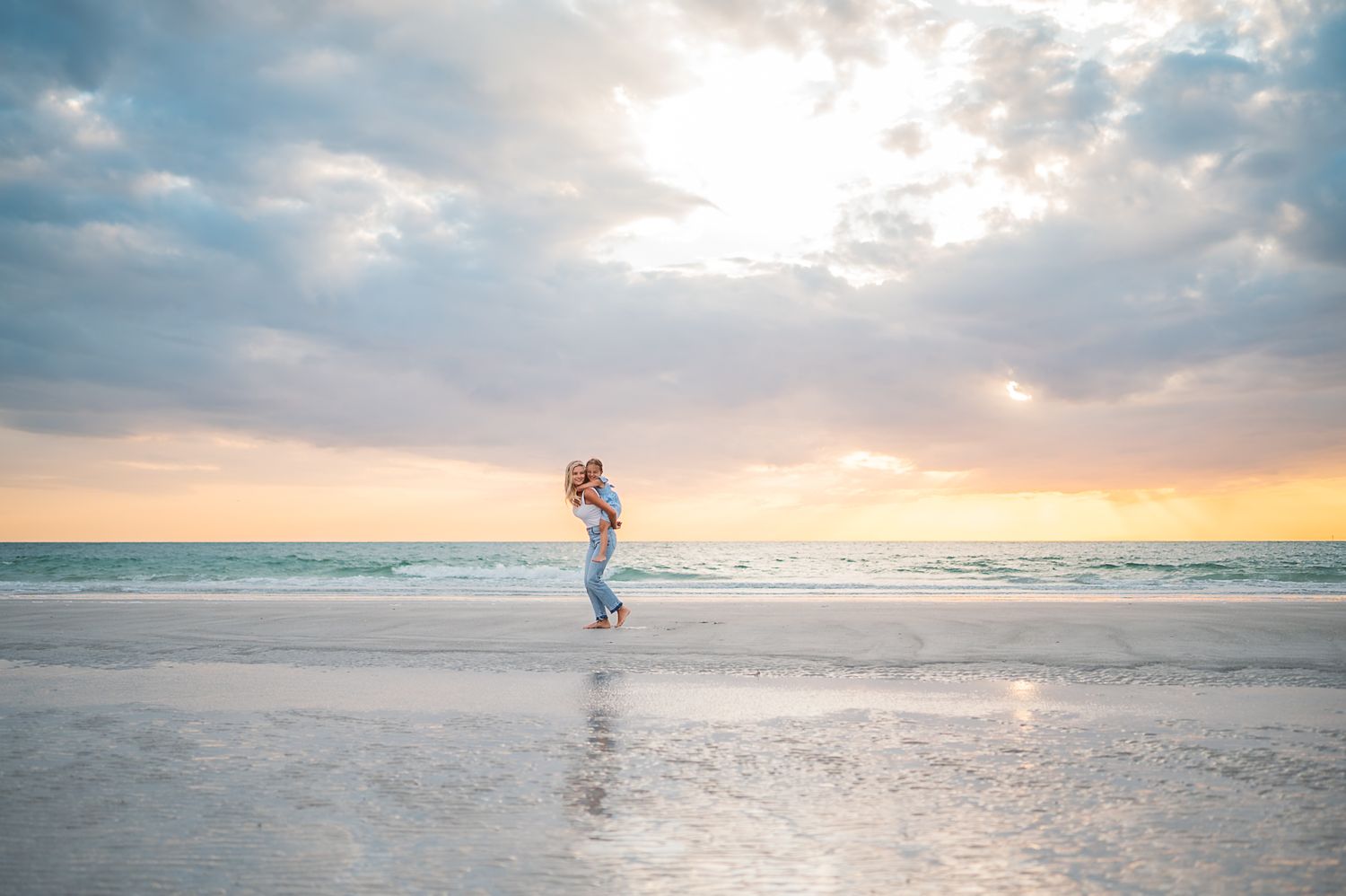 Dreamy beach scene at sunset with soft clouds and gentle waves rolling onto shore.