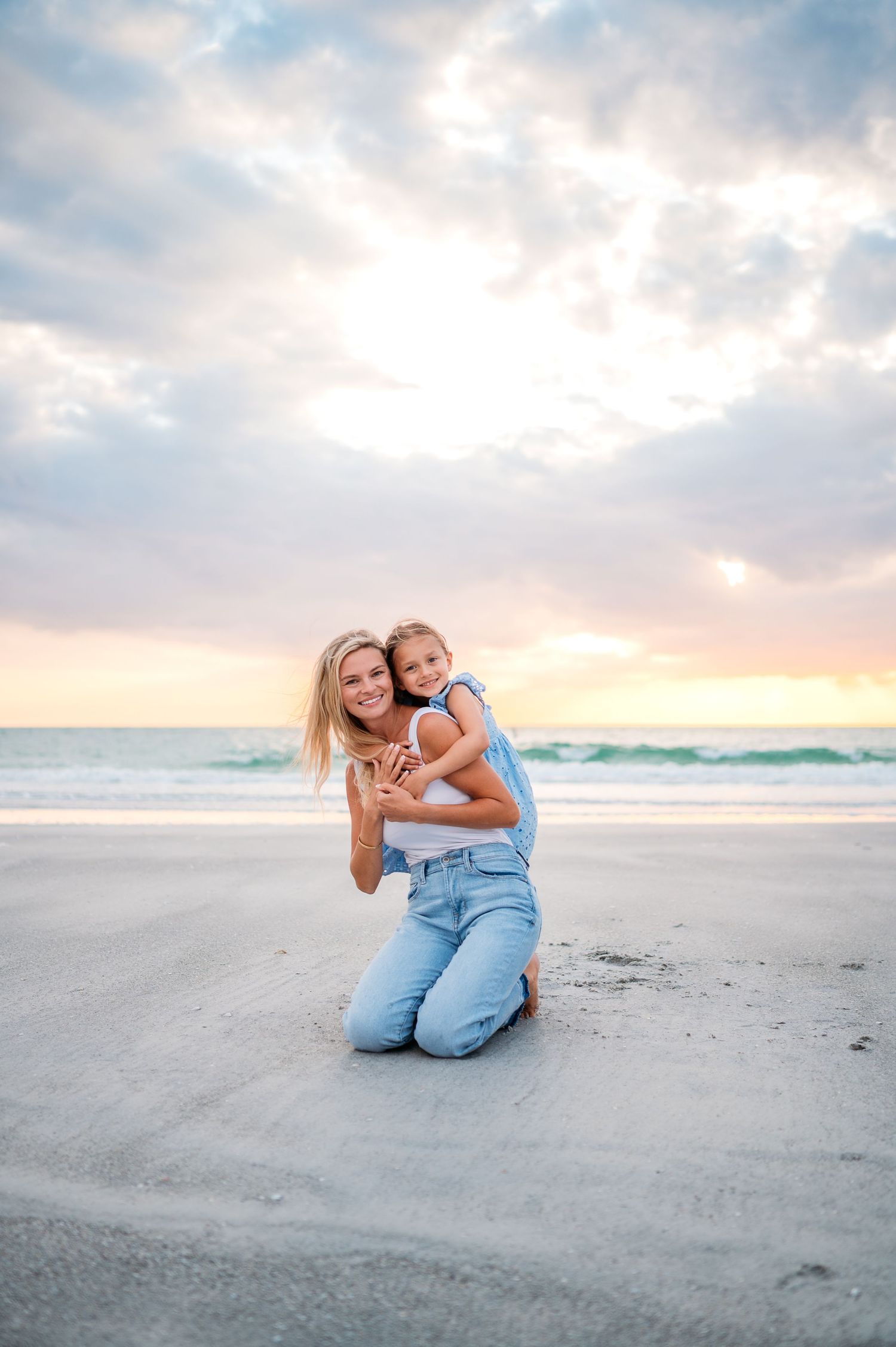 Tender beach moment captured at sunset with soft clouds and sandy shores.