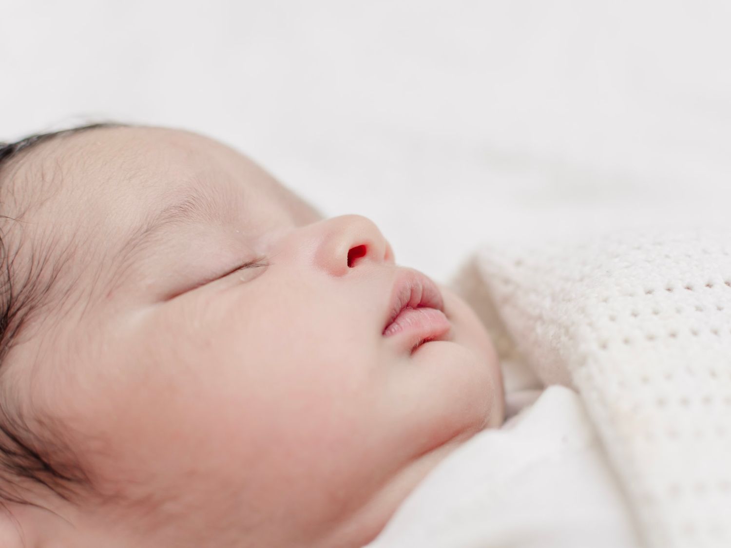 Newborn baby sleeping on cream blanket, lifestyle newborn photography in Essex