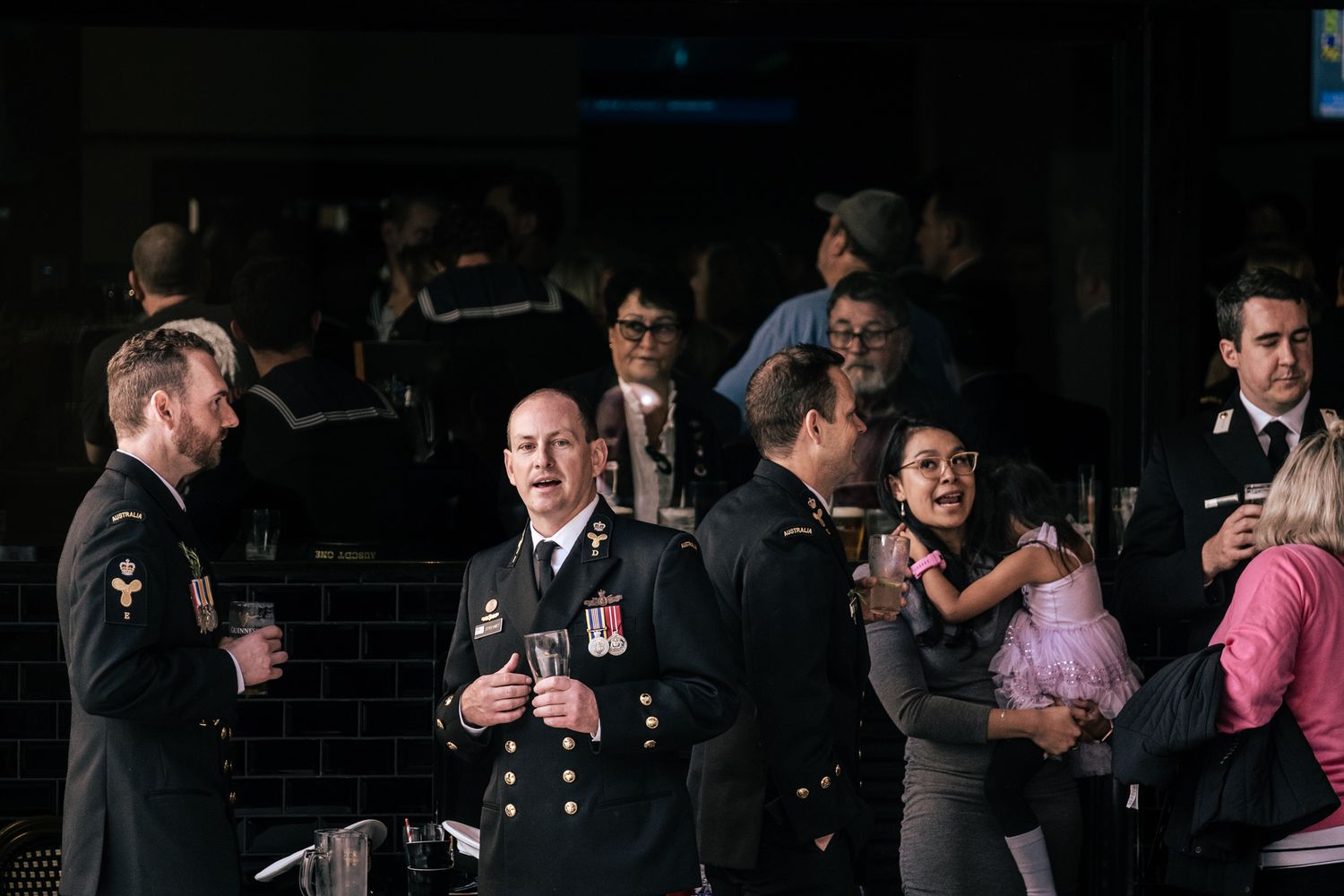 Military officers in uniform socializing at a formal evening event with drinks.