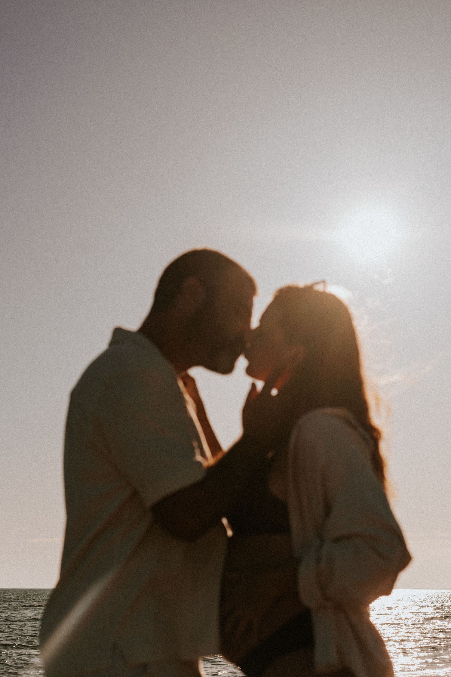 Couple attendant un enfant lors d'une séance grossesse au coucher du soleil sur une plage.