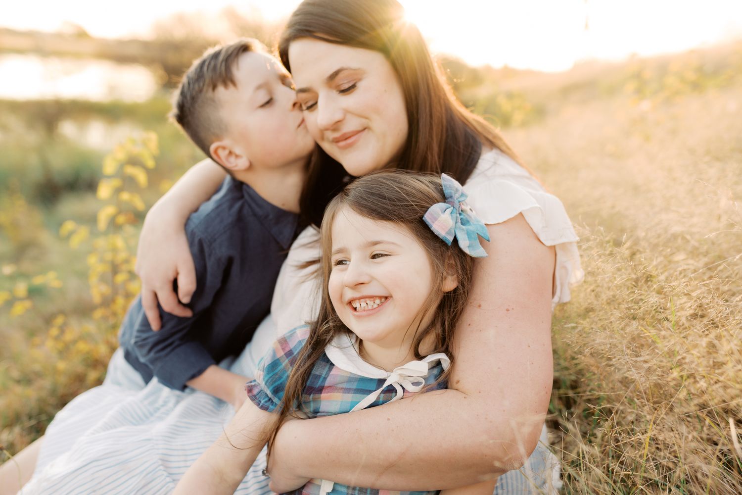 Mother sitting on hillside cuddling with her two children, Wollongong Family Photography.