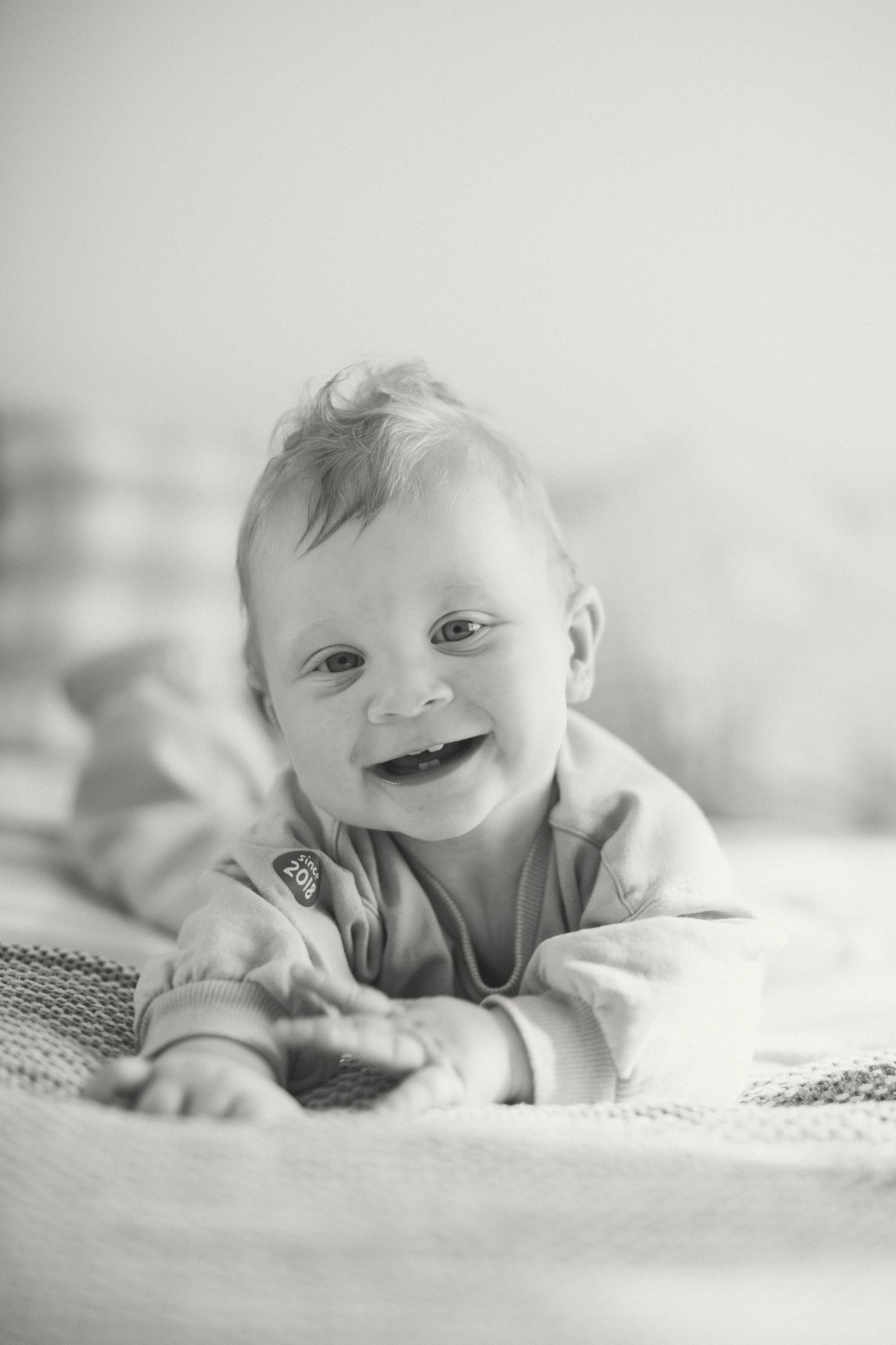 Baby boy smiling at camera during tummy time.