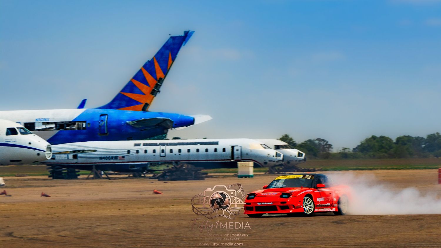 Red drift car doing a burnout in front of a parked airplane on a runway in Arkansas.