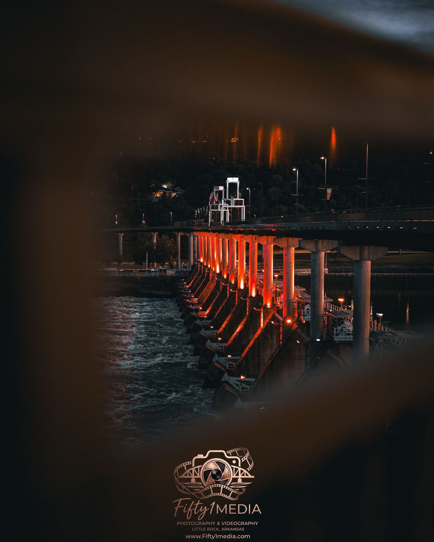 Moody nighttime photography showing glowing lights framed through a dark window or structure.